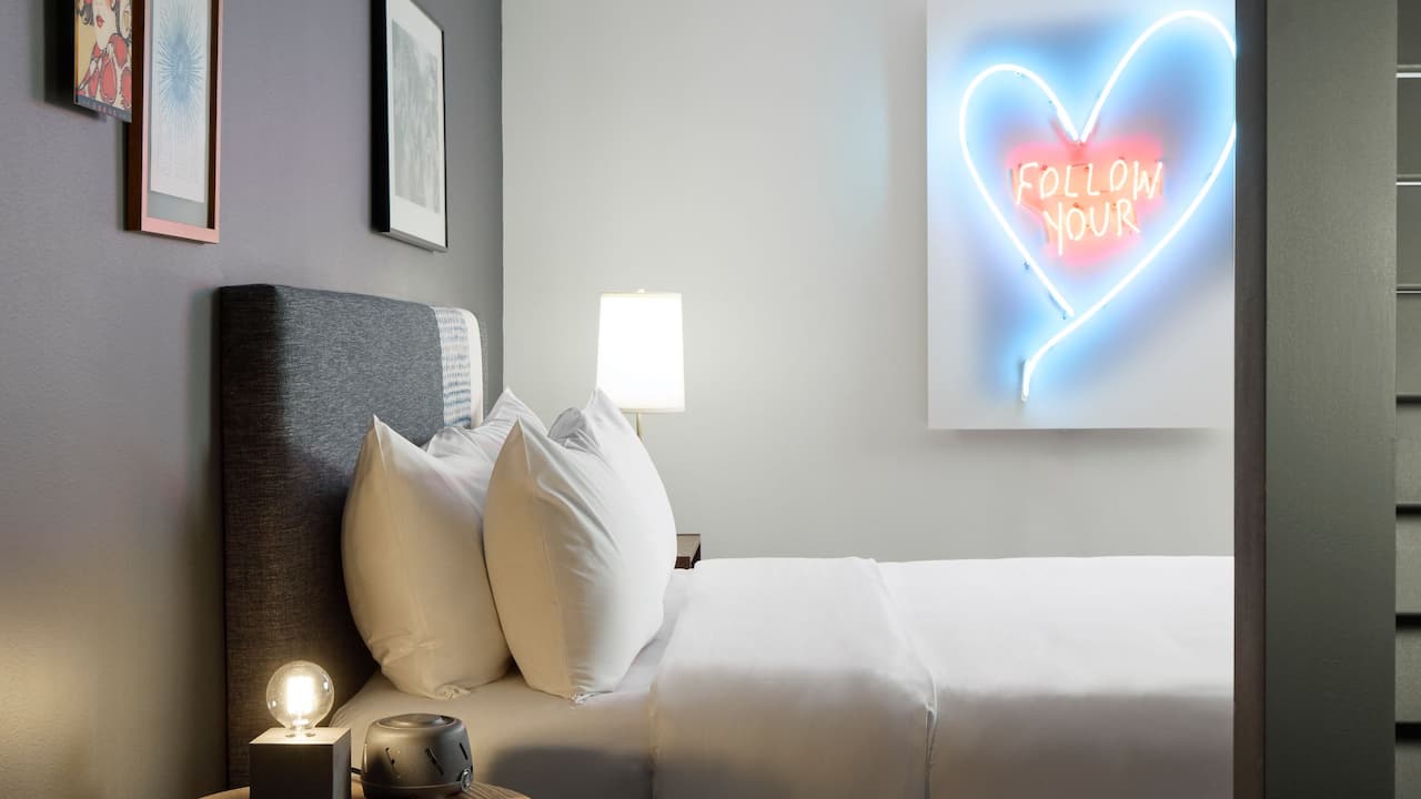 Consulate Suite with one king bed and neon lighting wall art