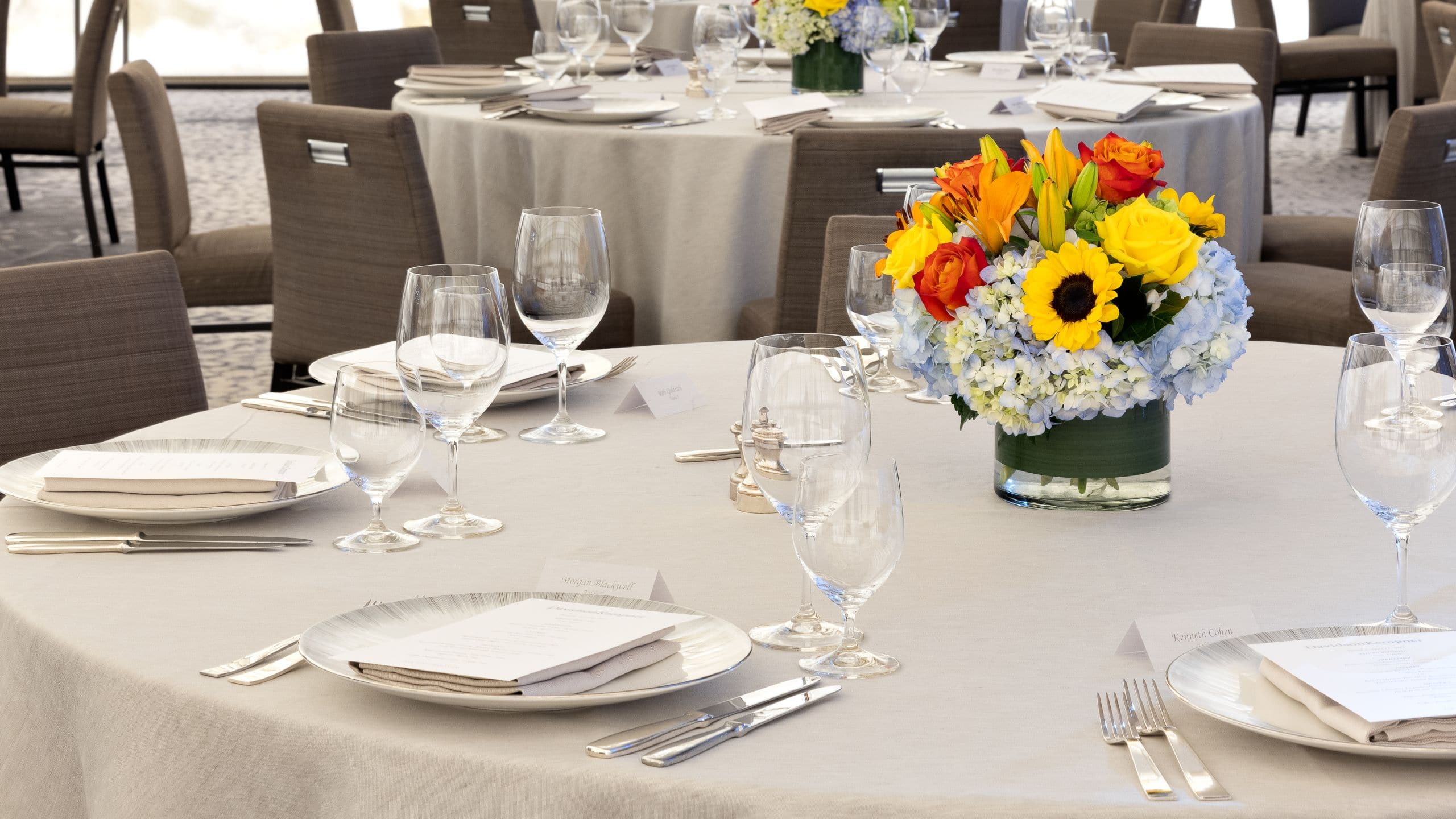 Ballroom with round tables with place settings and a flower arrangement