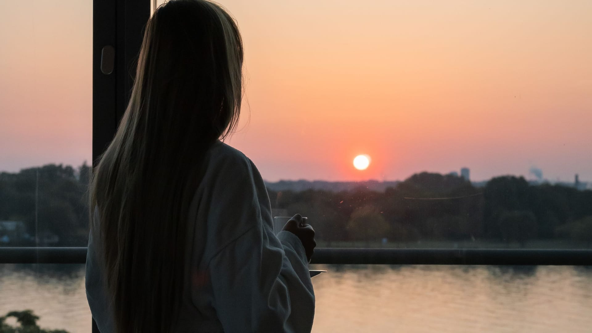 Woman watching sunset over the Rhine from hotel room at Hyatt Regency Mainz