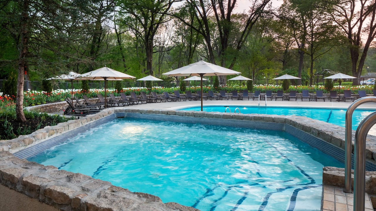 Outdoor heated pool with loungers and sun umbrellas