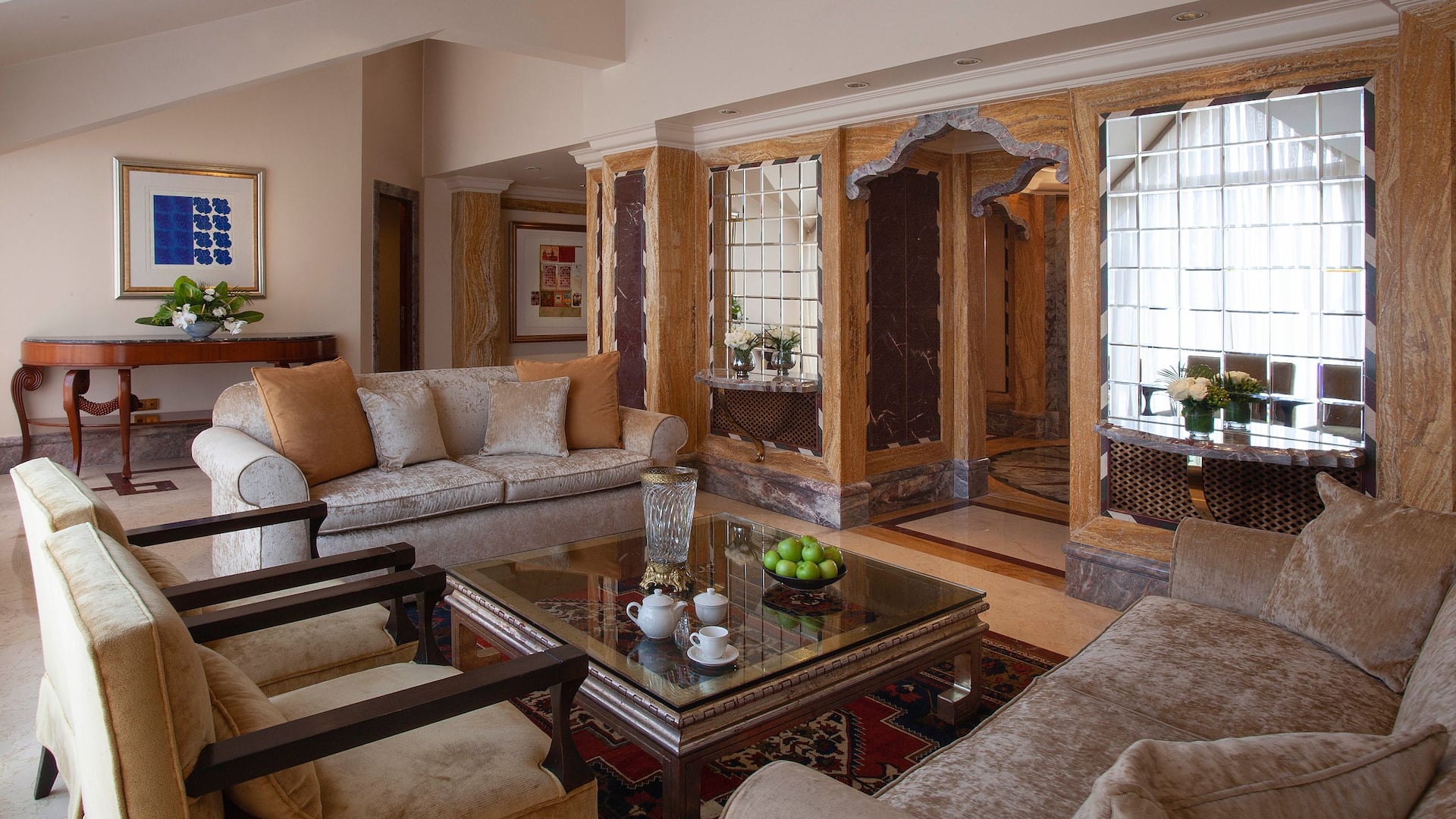 Ambassador Suite at Grand Hyatt Istanbul with luxury living area, covered with marble walls, ornate mirrors, soft-colored furnishings, artworks, and a coffee table with amenities.