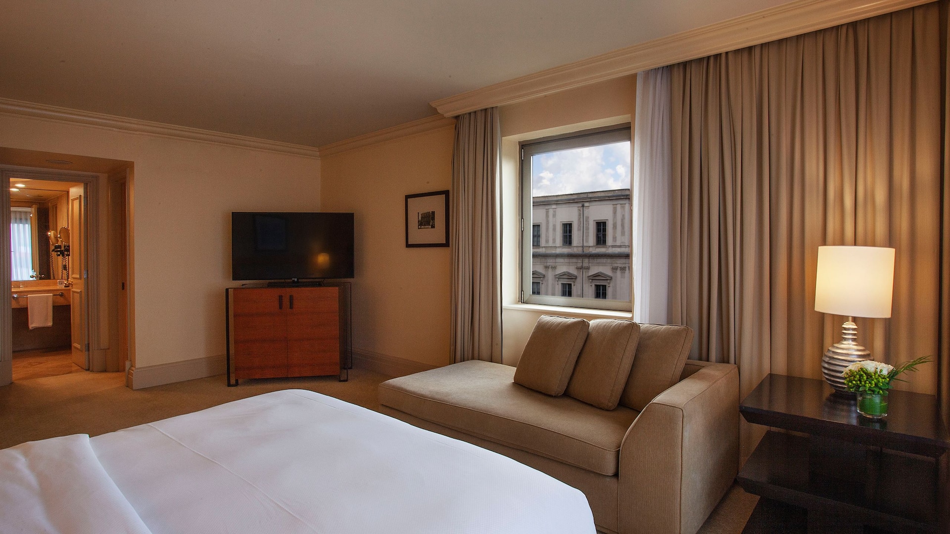 Grand Suite King room at Grand Hyatt Istanbul with spacious layout with king size bed, tv screen, armchair, bathroom area and iconic city view.