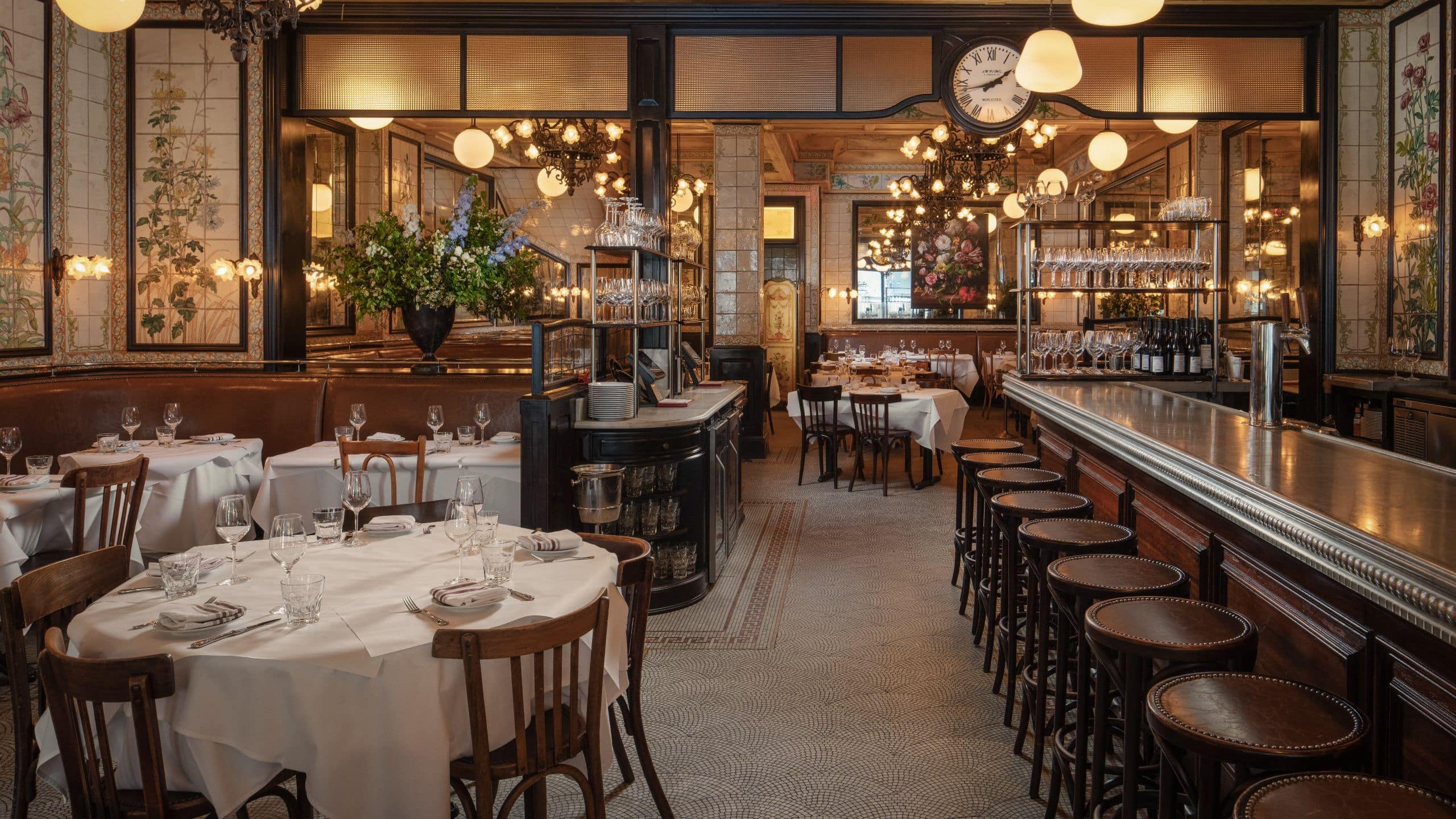 The dining room and bar at Le Gratin with set tables, chairs and a long bar with stools