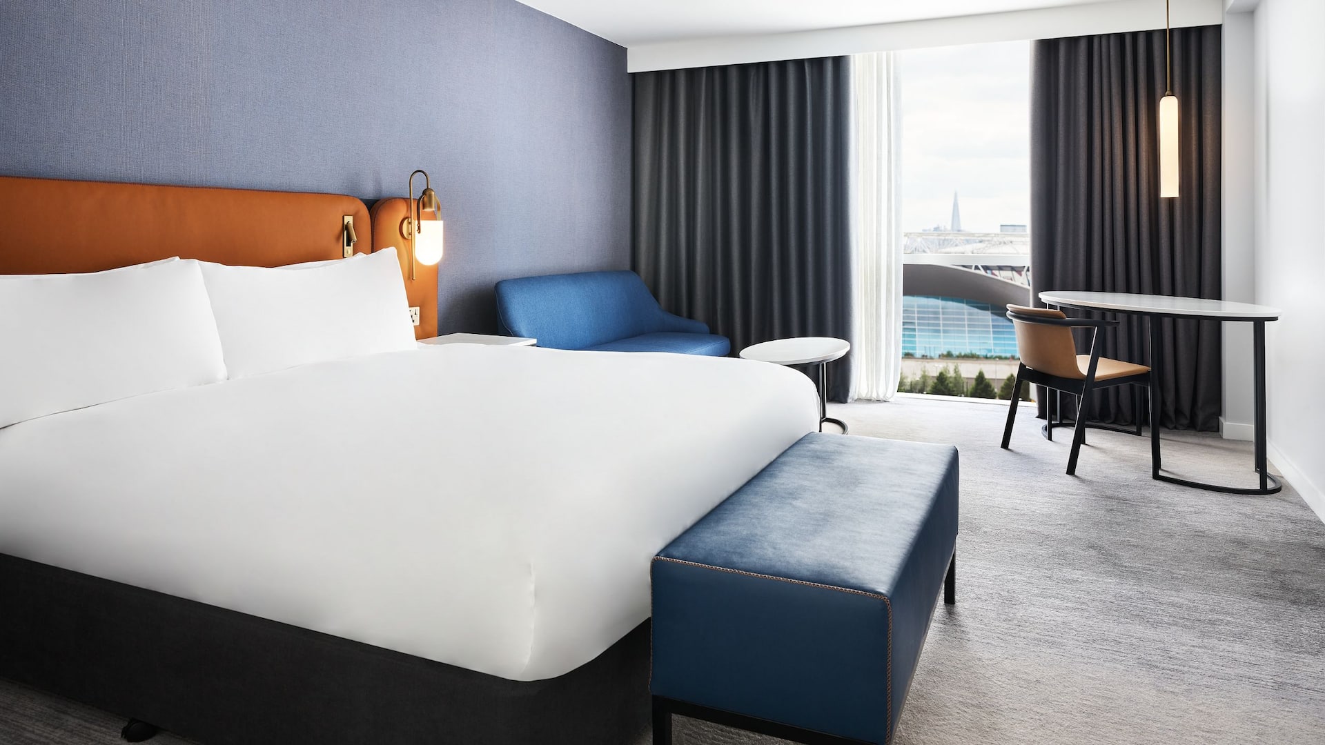 Deluxe bedroom at Hyatt hotel in Stratford, featuring a large double bed, a mini-bar, a TV and a desk with a chair