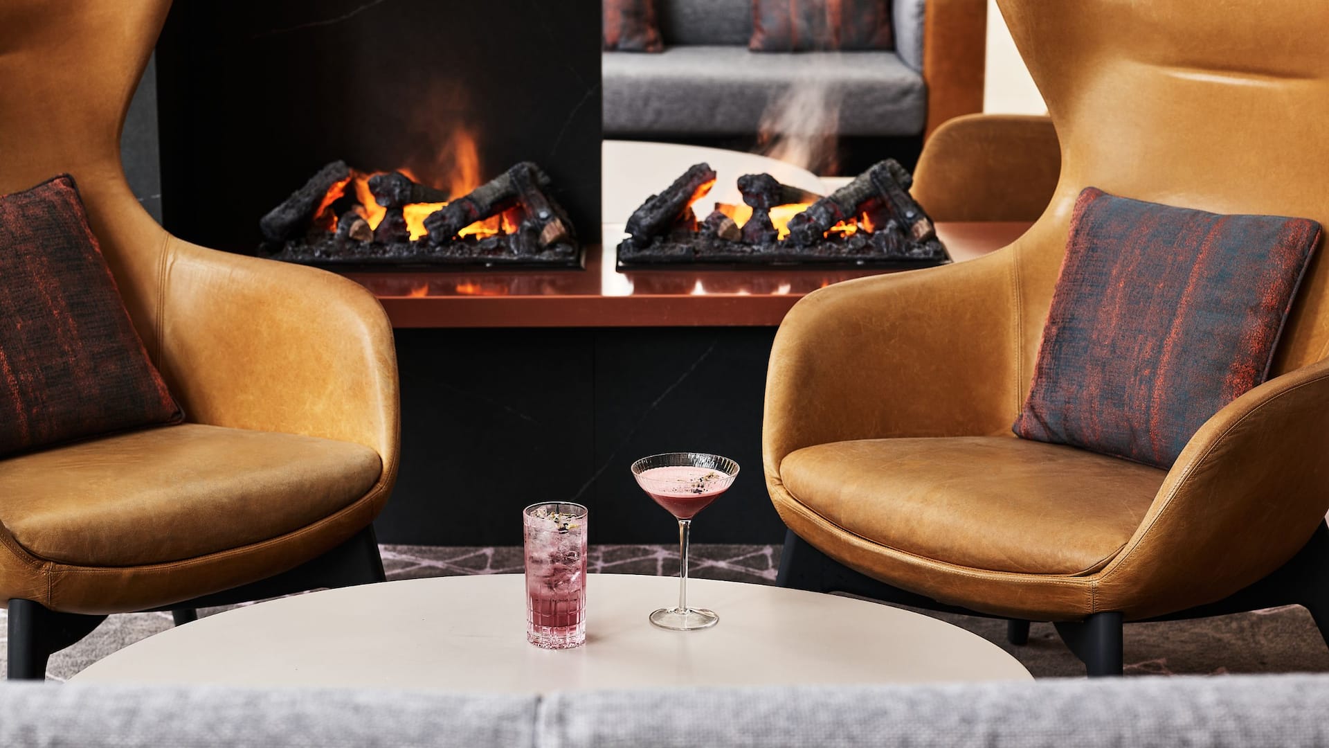 Two brown leather chairs in front of a modern fireplace with cocktails in Hyatt Regency Lobby