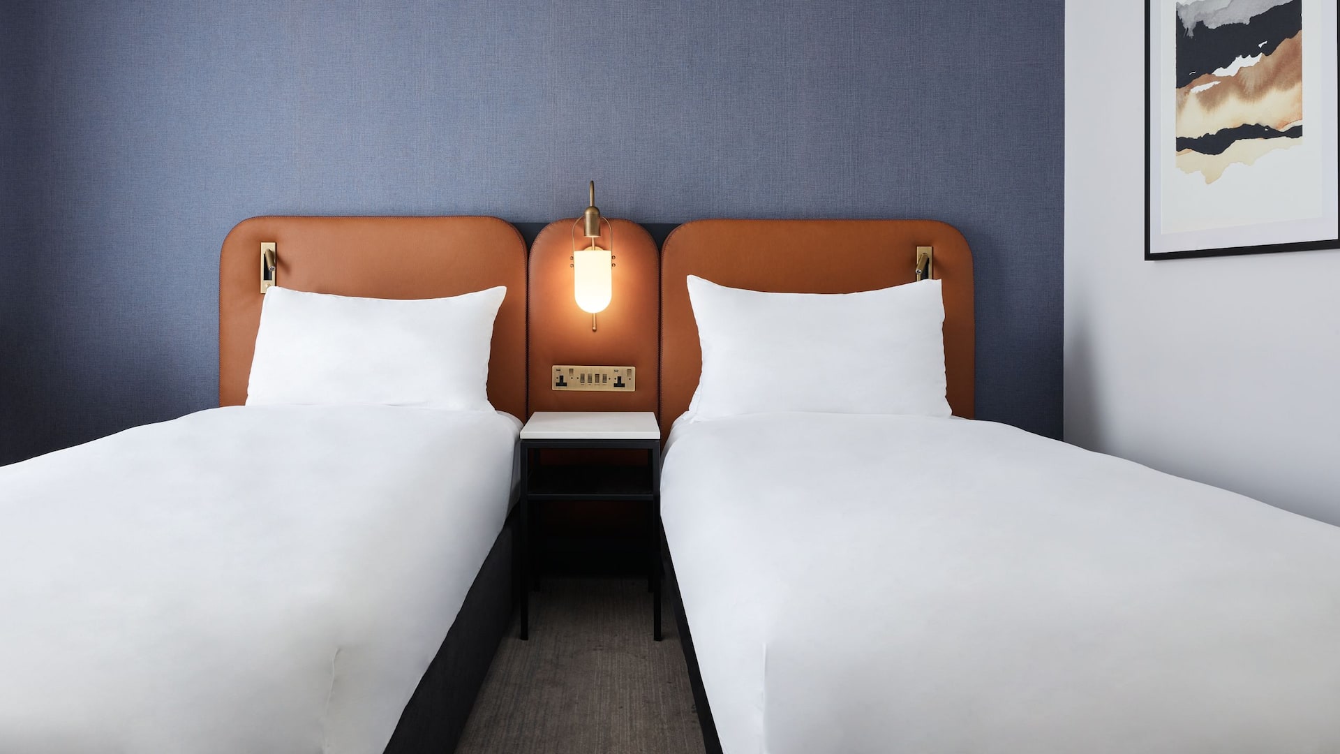 Twin beds next to each other in a 4-star hotel bedroom in East London, with 24/7 service available