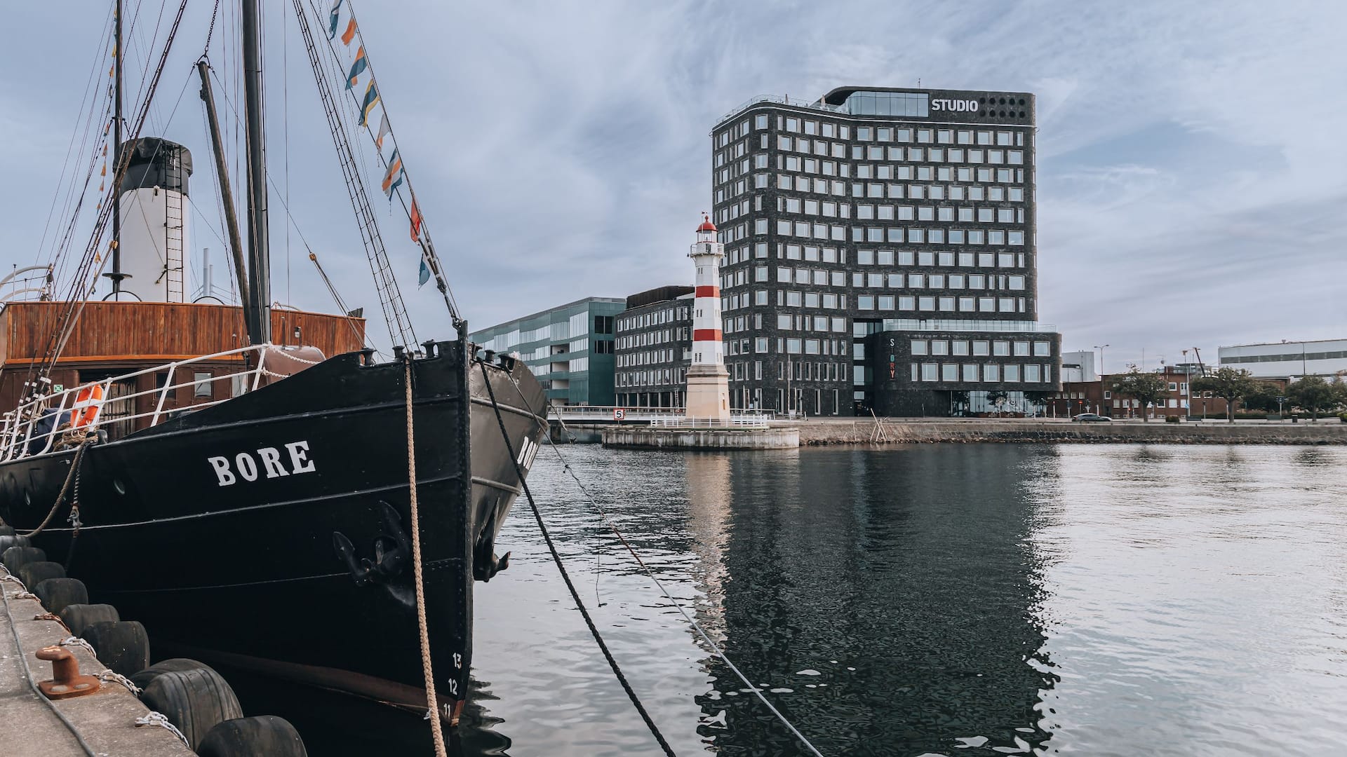 Story Hotel Studio Malmö och Malmö inre fyr, taget från vattnet med fartyget Bore i förgrunden