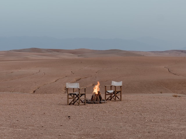 Two wooden chairs facing a small campfire in Agafay Desert, near Park Hyatt Marrakech