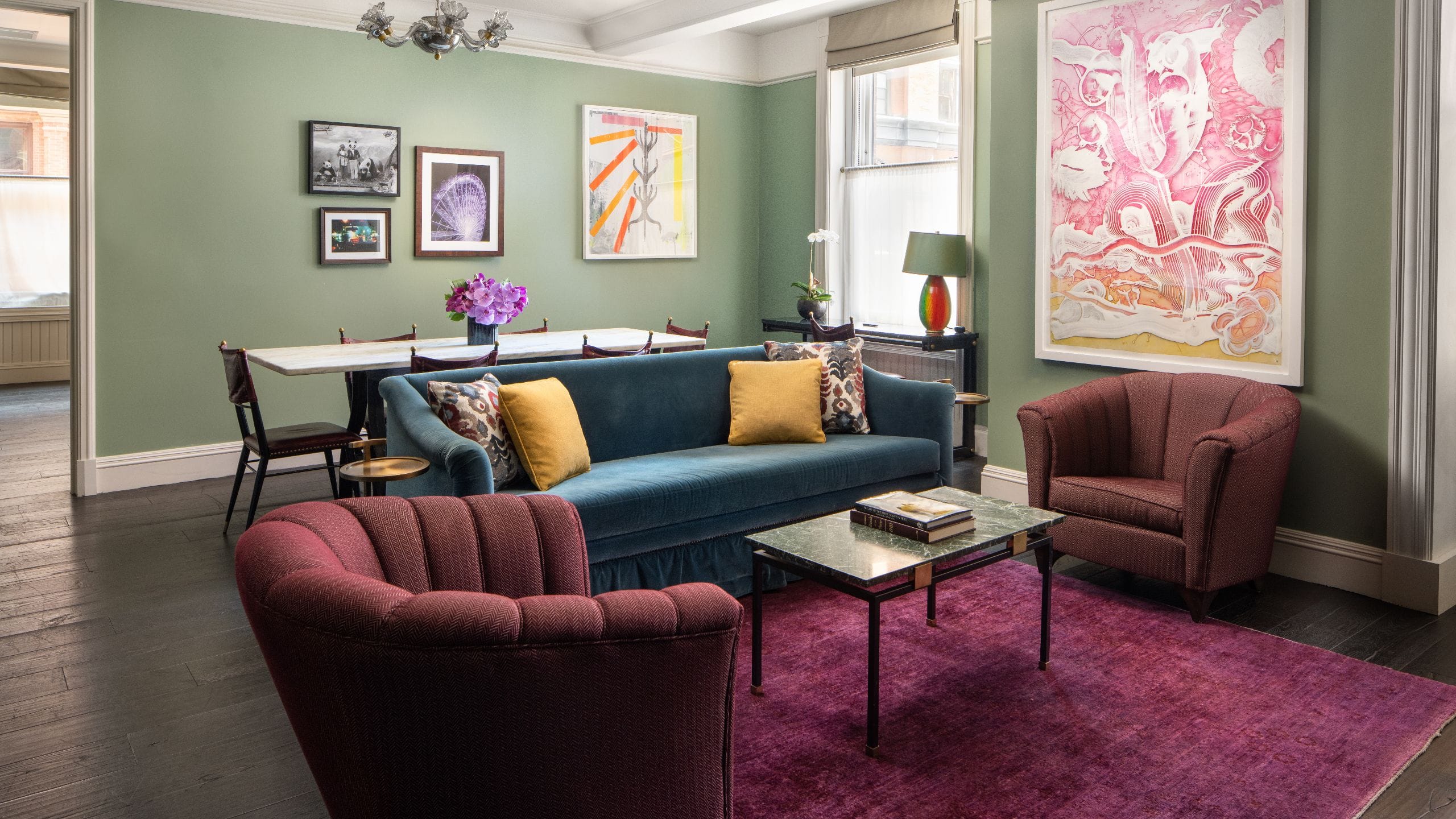 A suite living area with a long dining table and chairs and a sofa with two side chairs