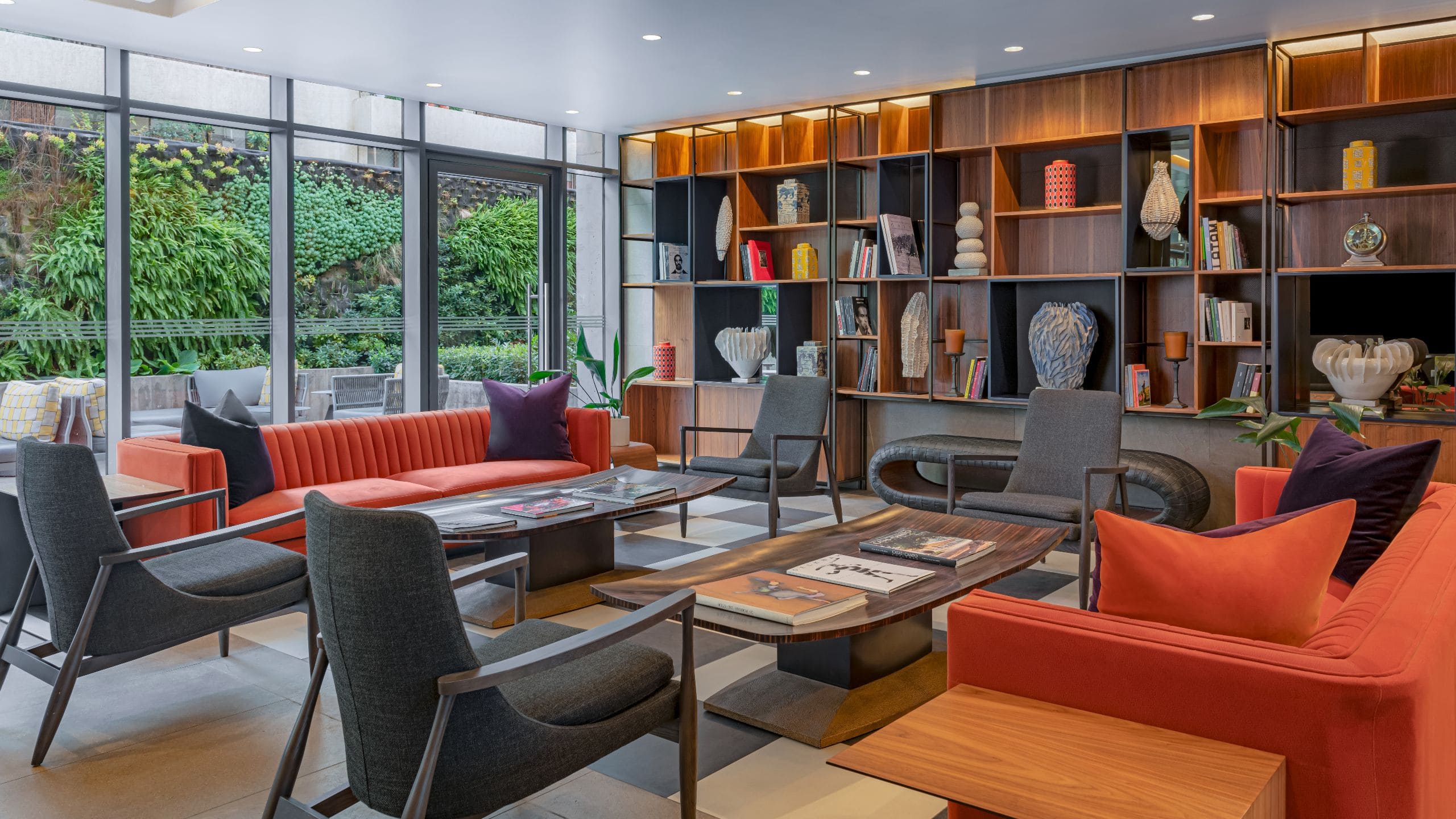 Lobby seating area with chairs, sofas, benches and a wall length bookcase