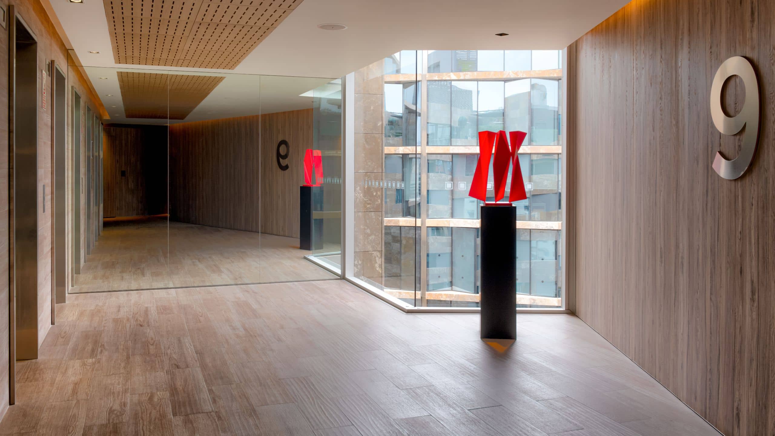 Foyer with elevator banks, floor to ceiling windows and modern sculptures