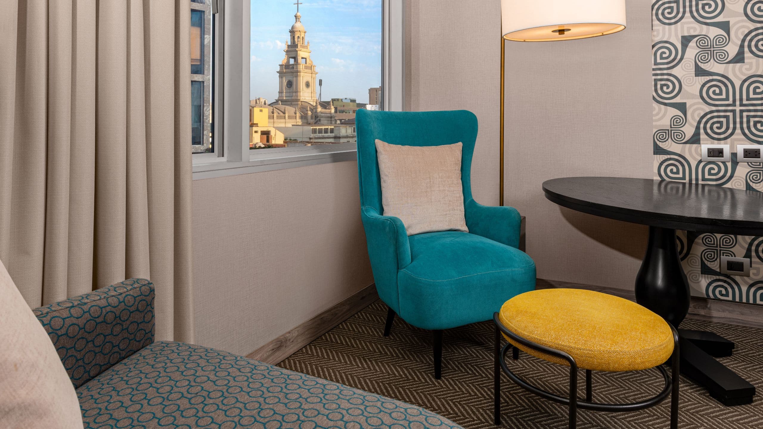 Guest room with small table, blue reading chair and view of the city