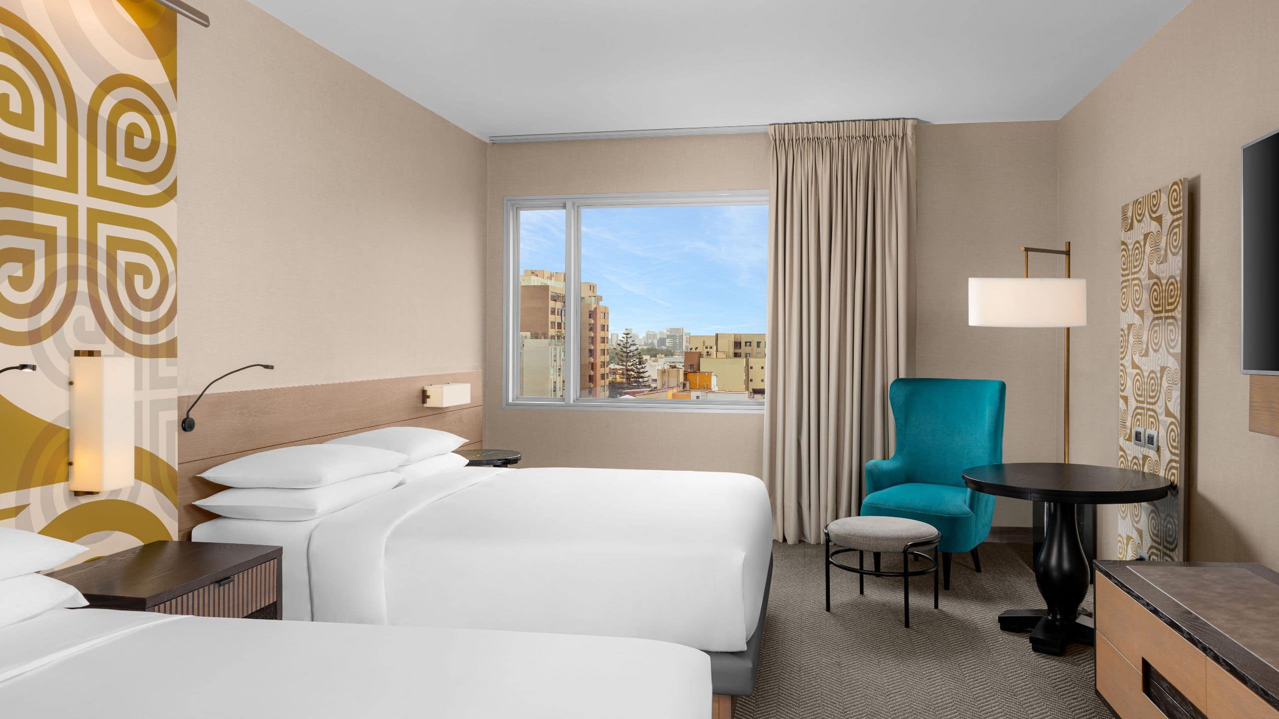 1/1 Two Queen Beds Deluxe guest room with large window, reading chair and small table