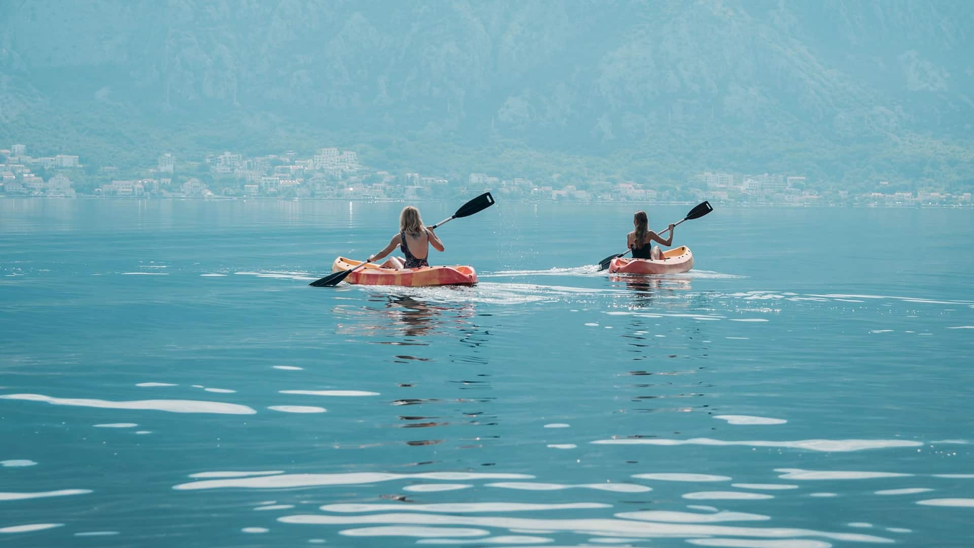 Guests kayaking in the clear waters of Kotor Bay, with a view of Hyatt Regency Kotor Bay Resort, Montenegro, in the background.