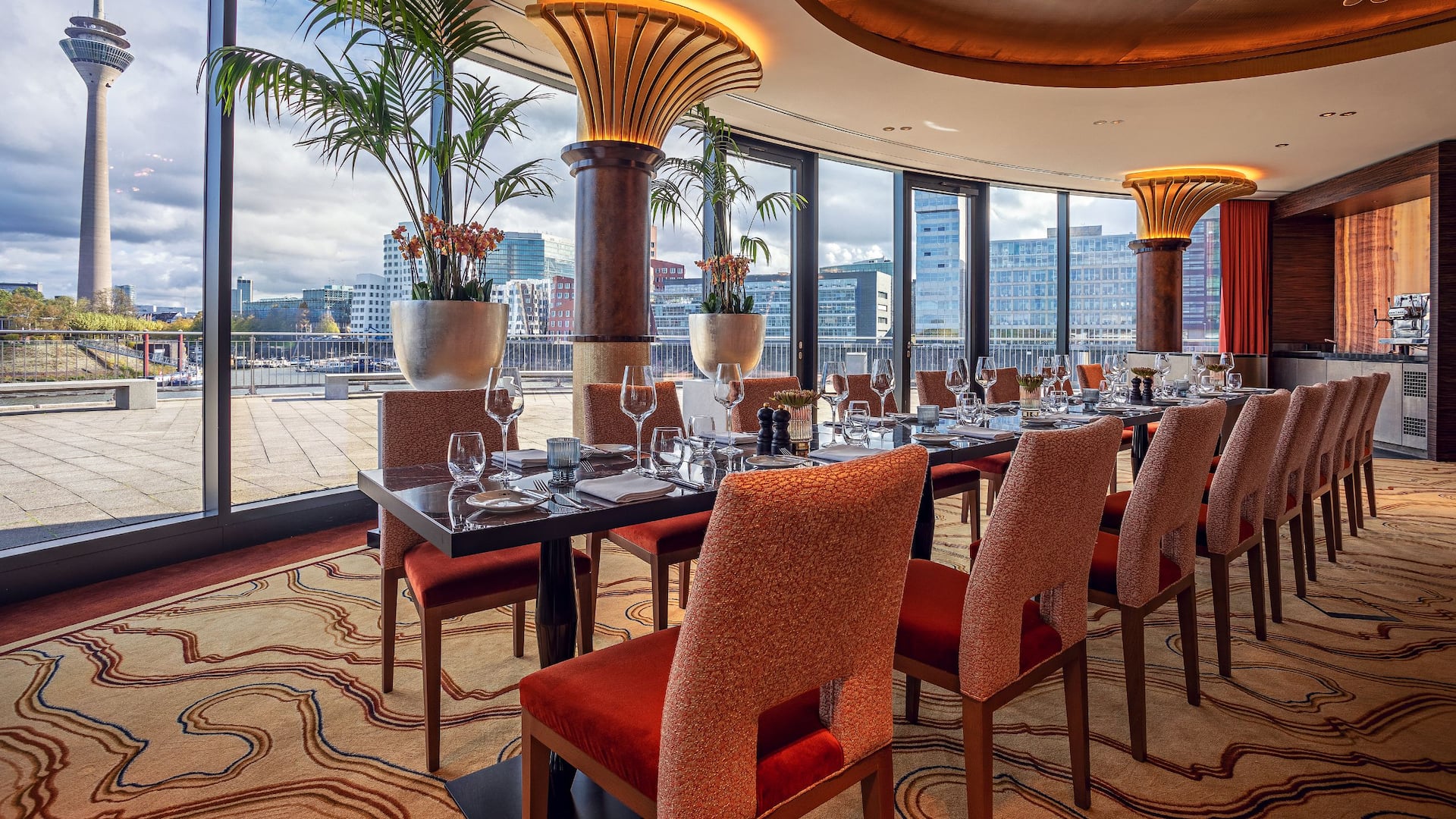 River Salon at Hyatt Regency Dusseldorf, with a posed table and a view of the TV tower in a warm design and golden chandelier