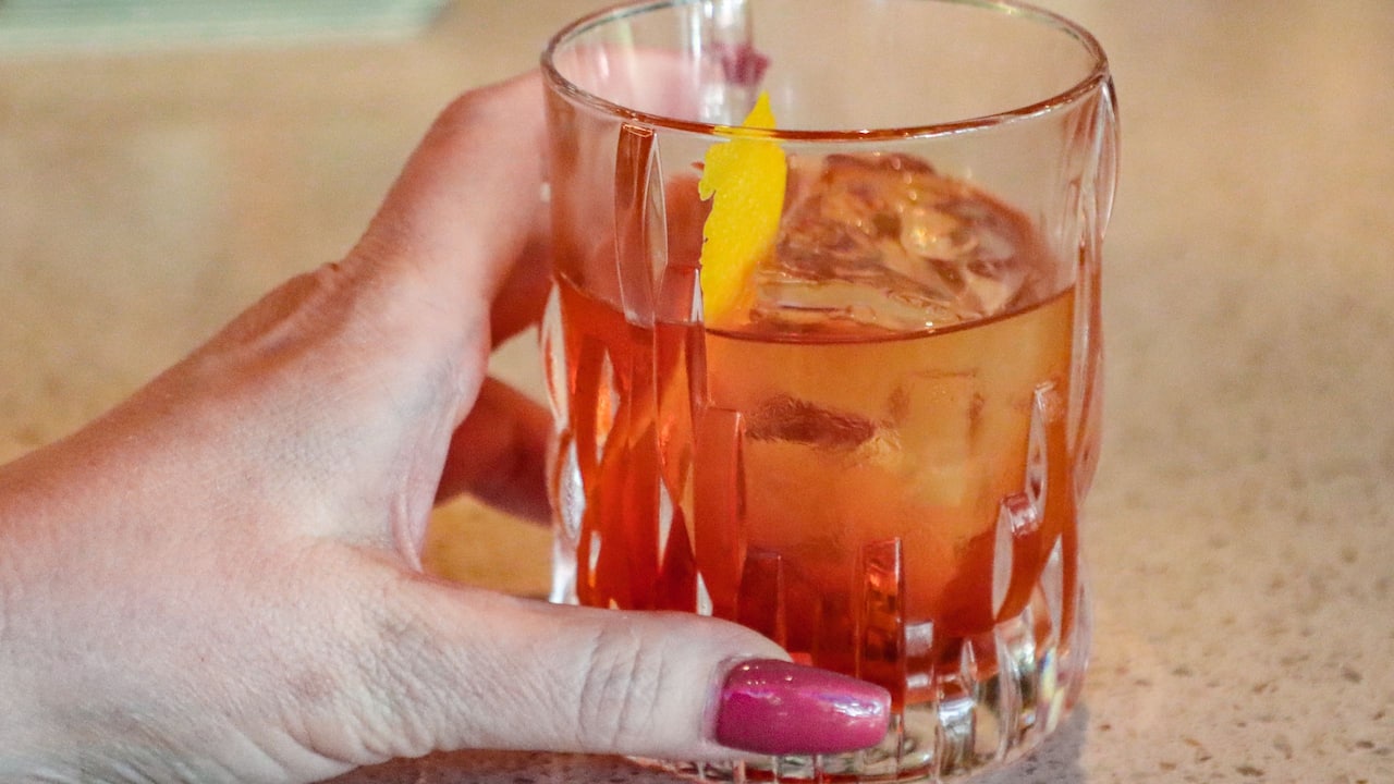 Hand holding old fashioned cocktail