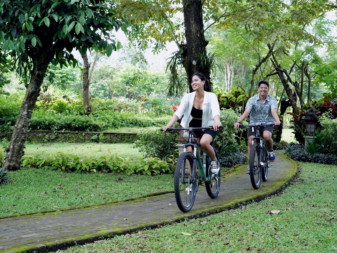 Couple cycling around Hyatt Regency Yogyakarta's jogging track amidst the scenic garden