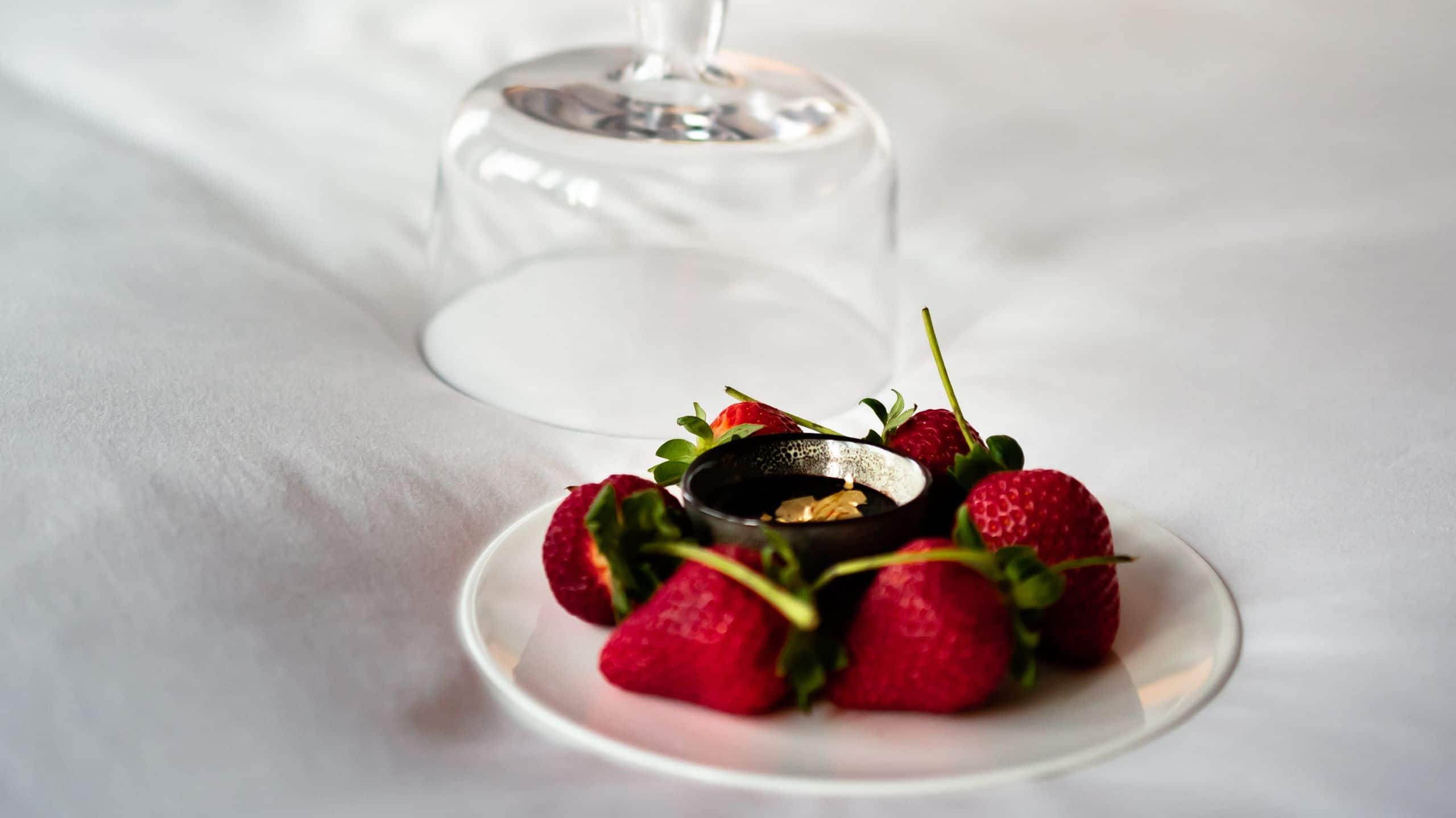 Berries on a plate on a bed with a lamp in the background 