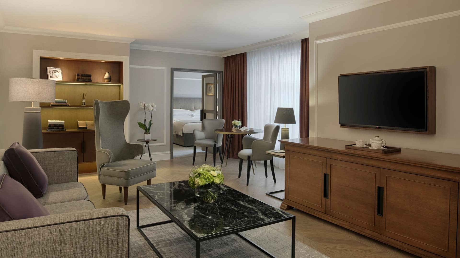 Executive suite living room with coffee table and dining table in the background and door leading to the bedroom.