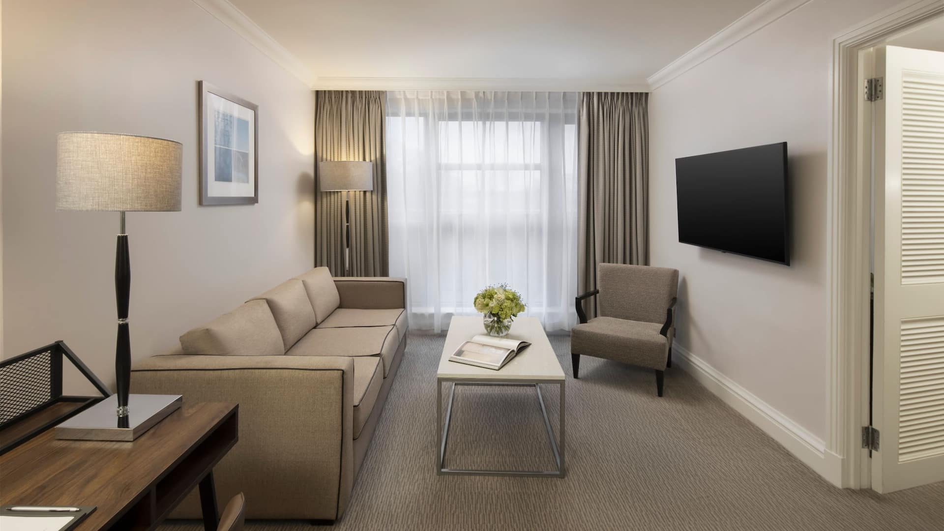 Interior of Regency Balcony Suite showing the spacious living room with a couch, armchair and coffee table book.