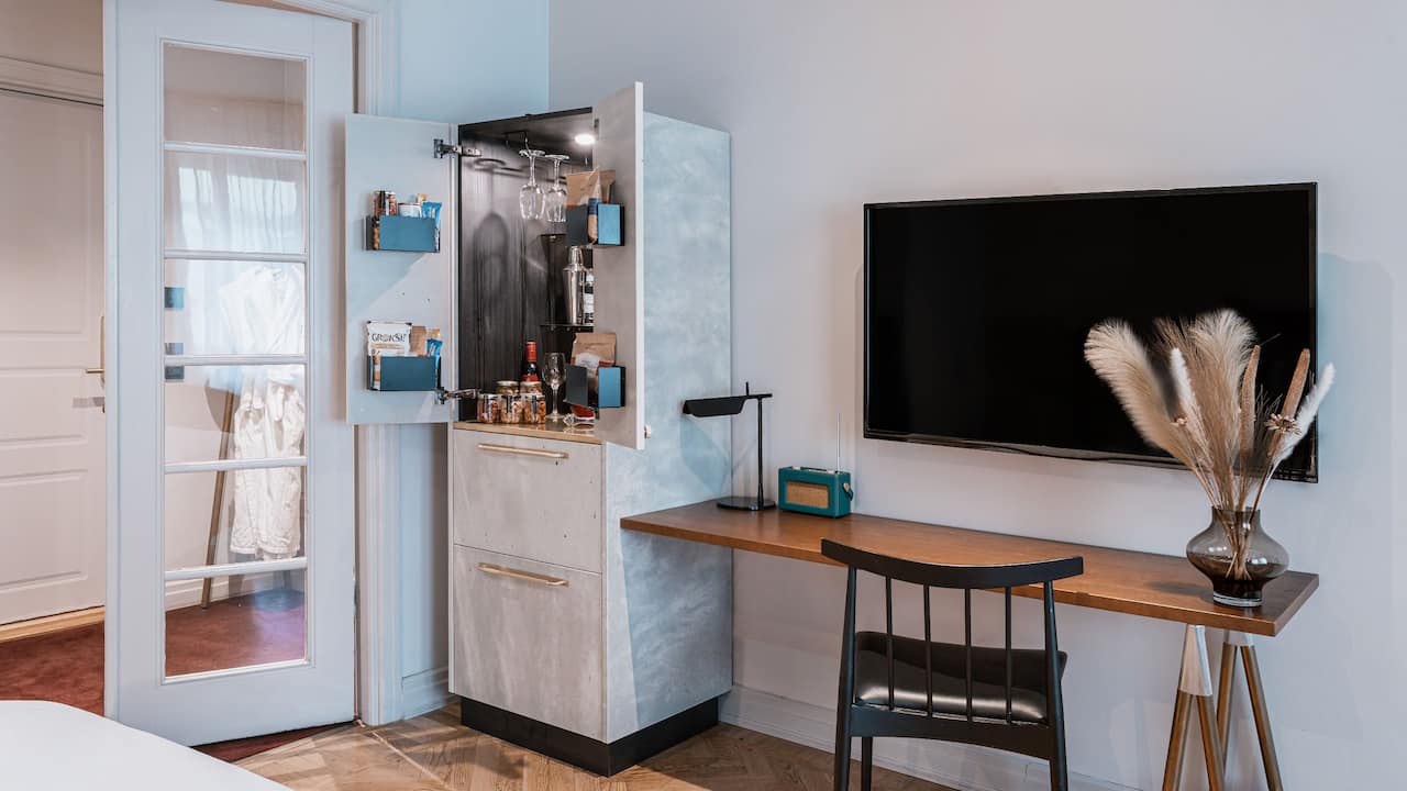 Cabinet, work desk, TV and fully stocked minibar in king bed deluxe room 