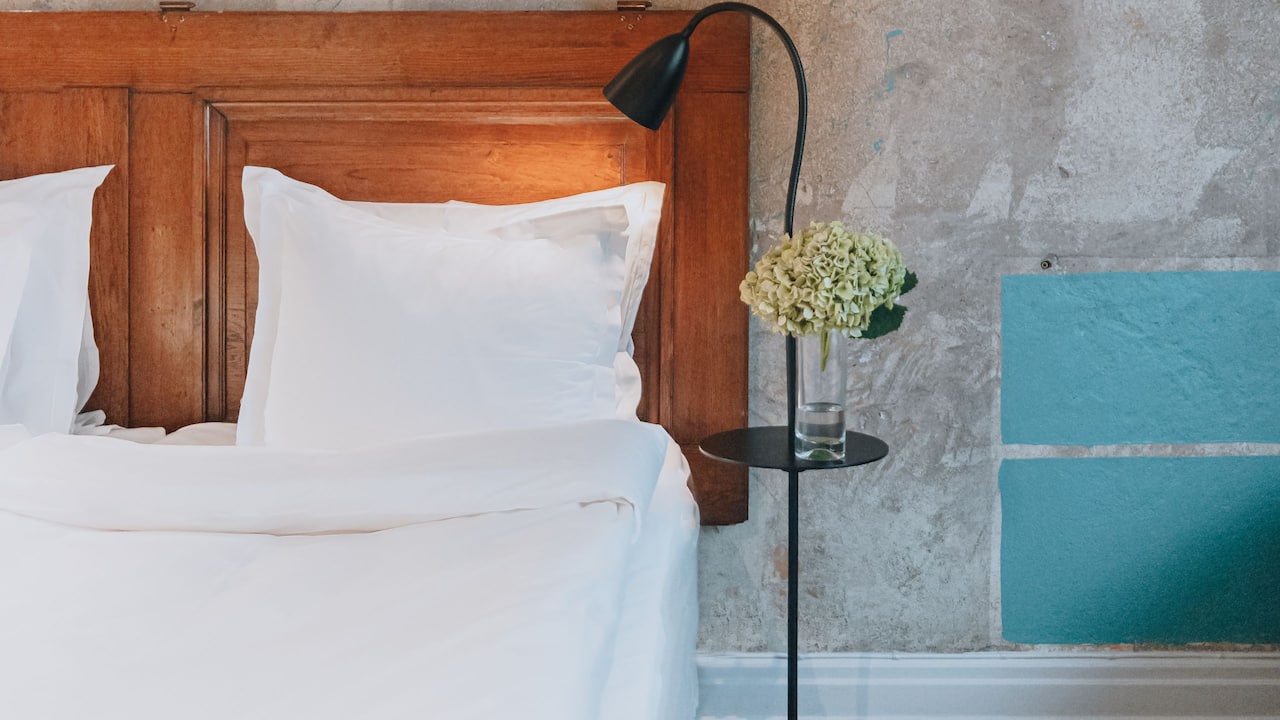 Room details, flower on bedside table, lamp and close up of bed