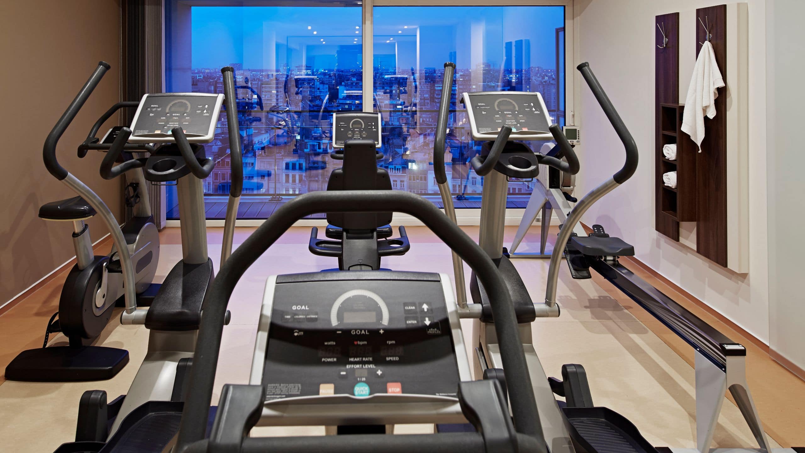 Heller Hotel-Fitnessraum mit modernen Geräten und Ausblick auf die Stadt 