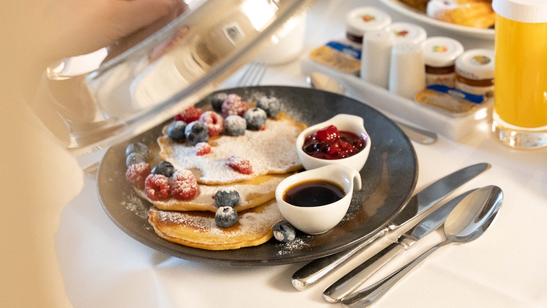 5 de 5 Woman opens plate cover of her breakfast in the room of Hyatt Regency Cologne