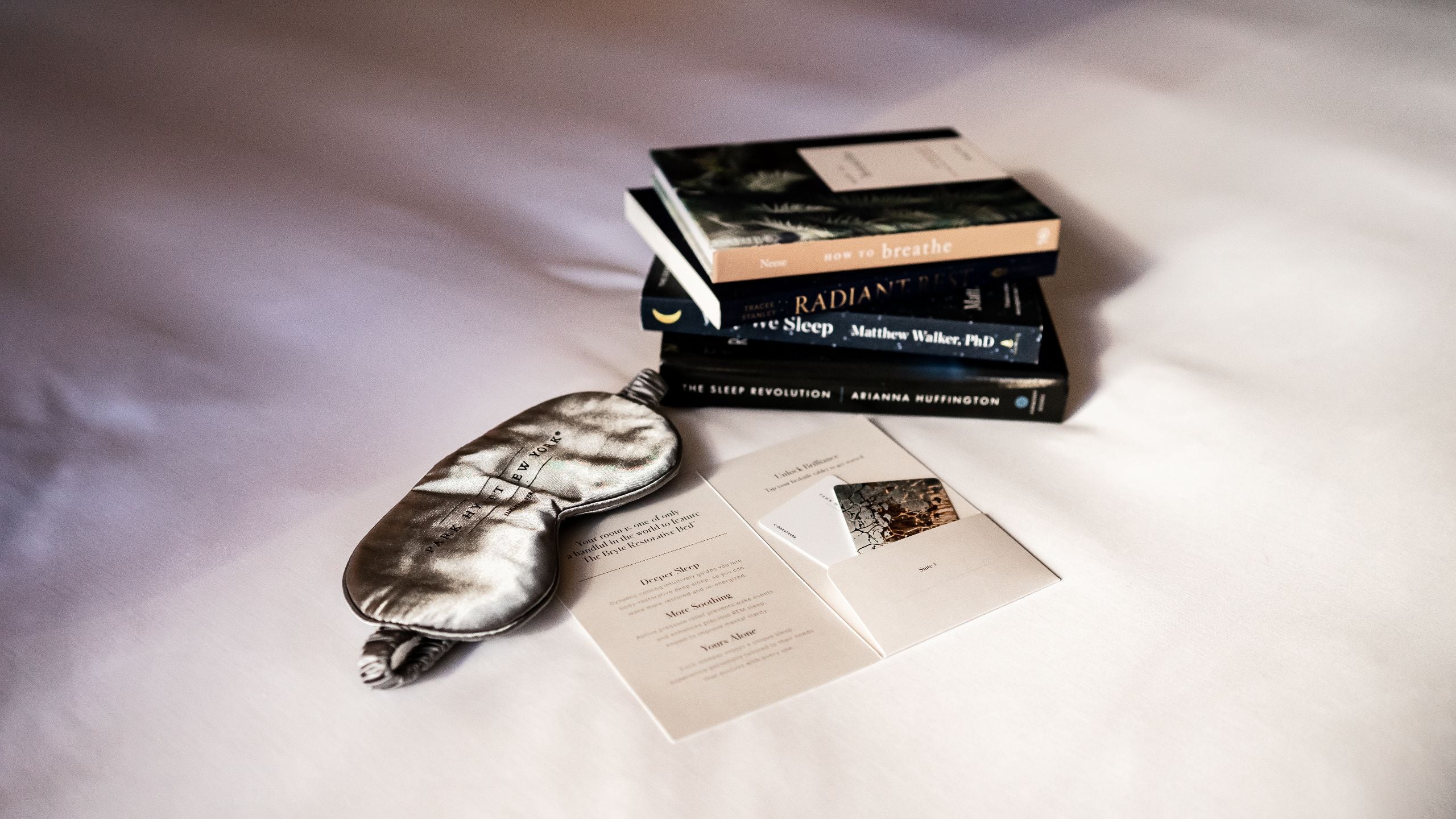 An eyemask, key card and other amenities placed on a bed