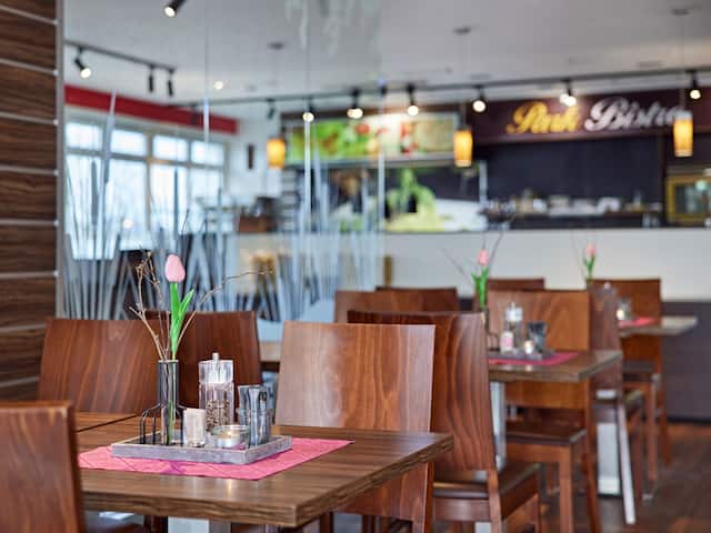 A modern furnished restaurant in a hotel at the Nürburgring with solid wooden tables and chairs.