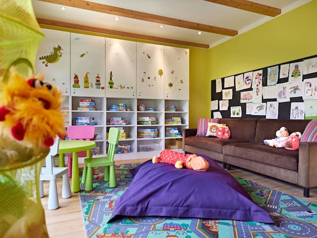 A modern furnished playroom for children in a hotel at the Nürburgring with dolls, several chairs, a couch, and other amenities for the little ones.