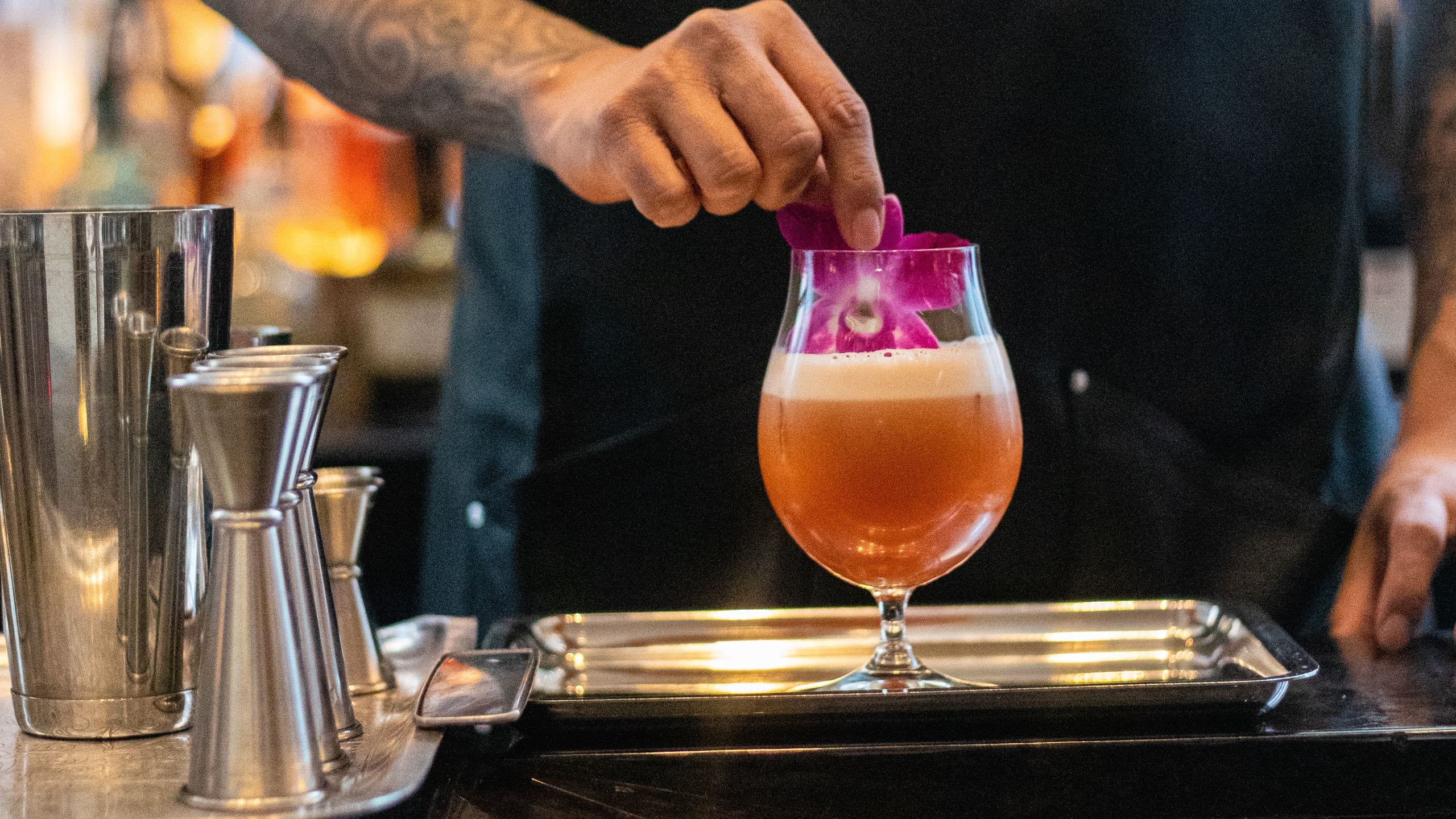 Bartender wearing an apron preparing a cocktail on a bar