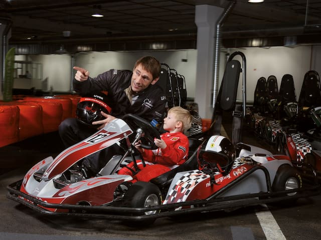 A small child and his father in a go-kart in a hotel at the Nürburgring.