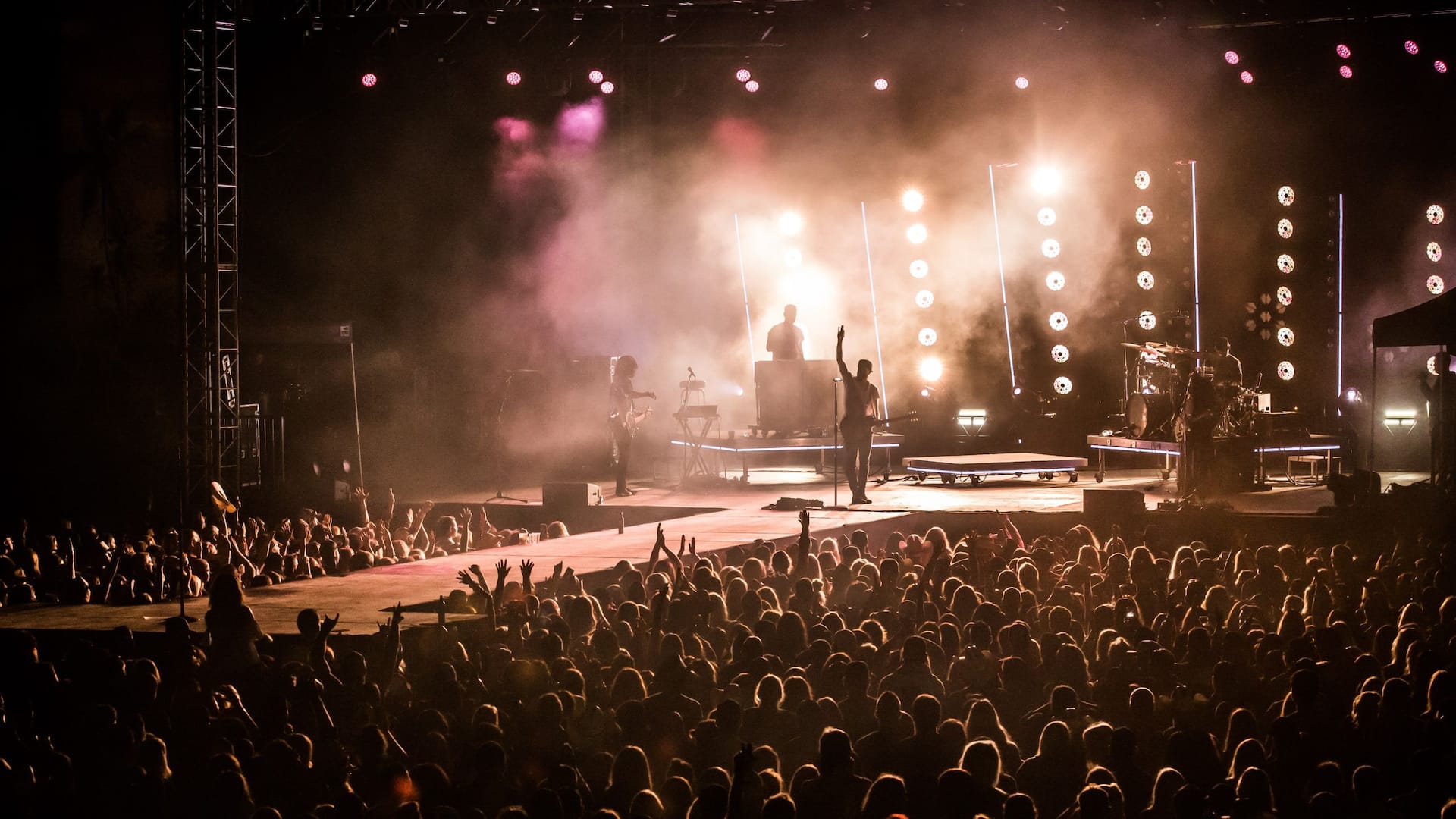 Concert stage set up, featuring vibrant lights and a cheering audience