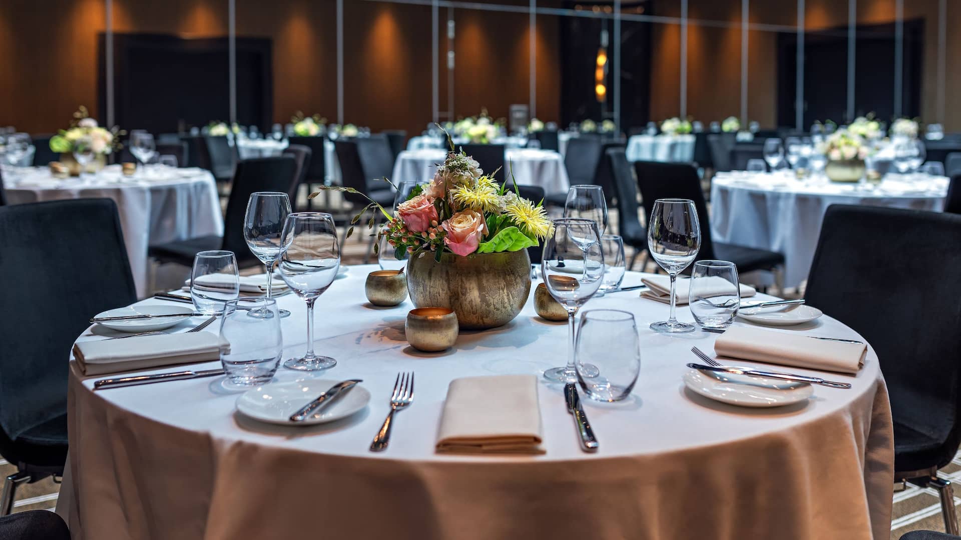 Ballroom at the Hyatt Regency Dusseldorf set with round tables and floral decorations on the table