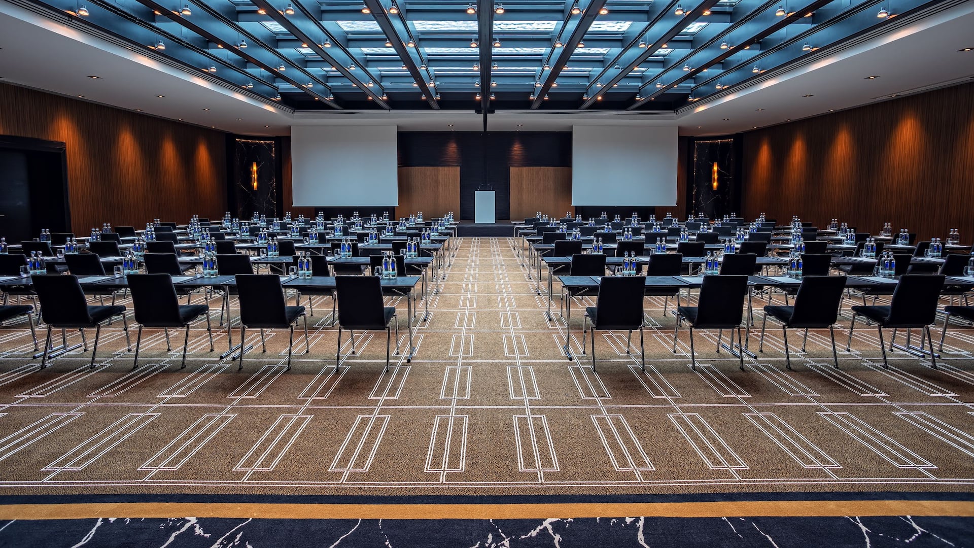 Ballroom at the Hyatt Regency Dusseldorf, with rows of chairs and screen with daylight through the water roof