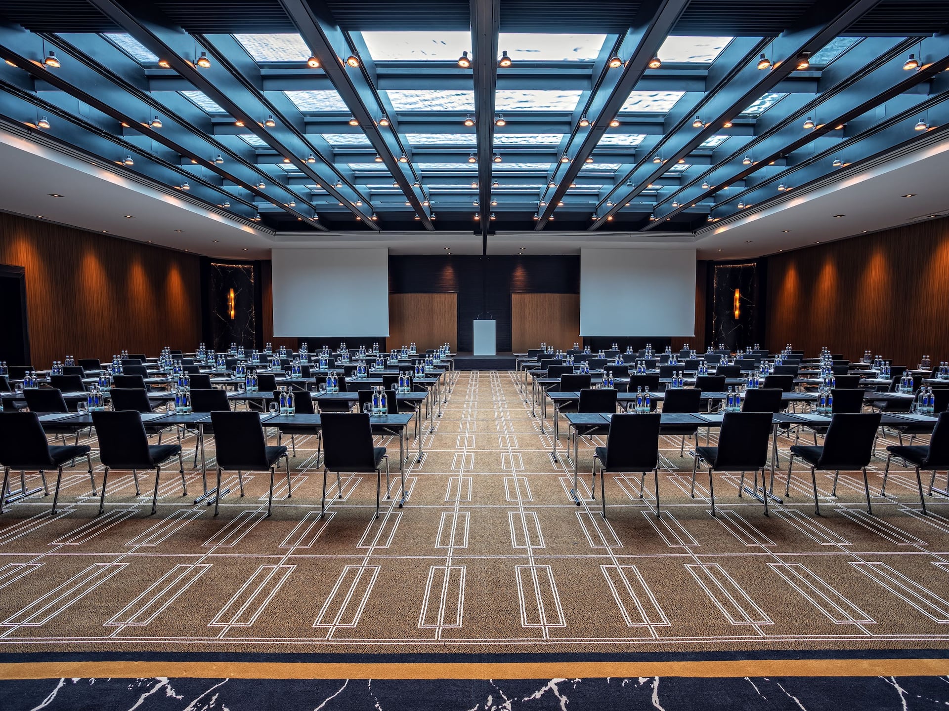 Ballroom at the Hyatt Regency Dusseldorf, with rows of chairs and screen with daylight through the water roof