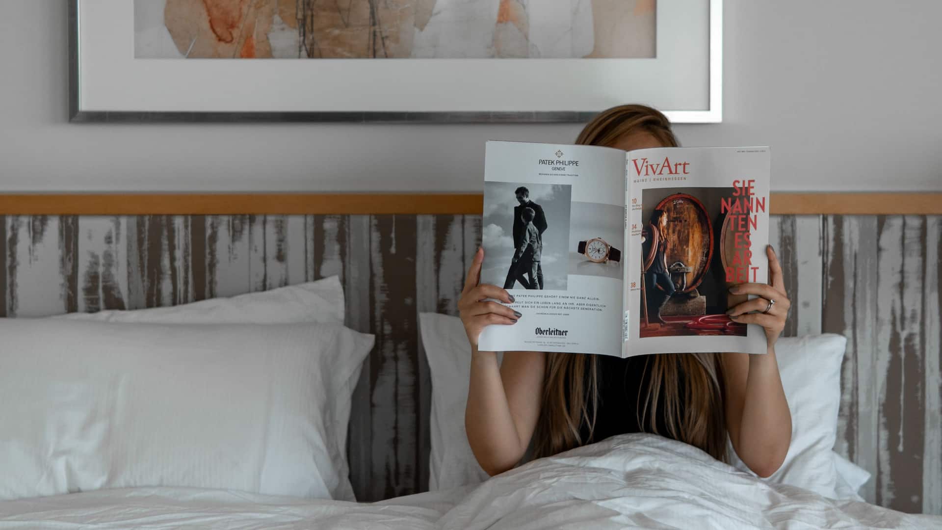 Woman reading a magazine in bed of Hyatt Regency Mainz