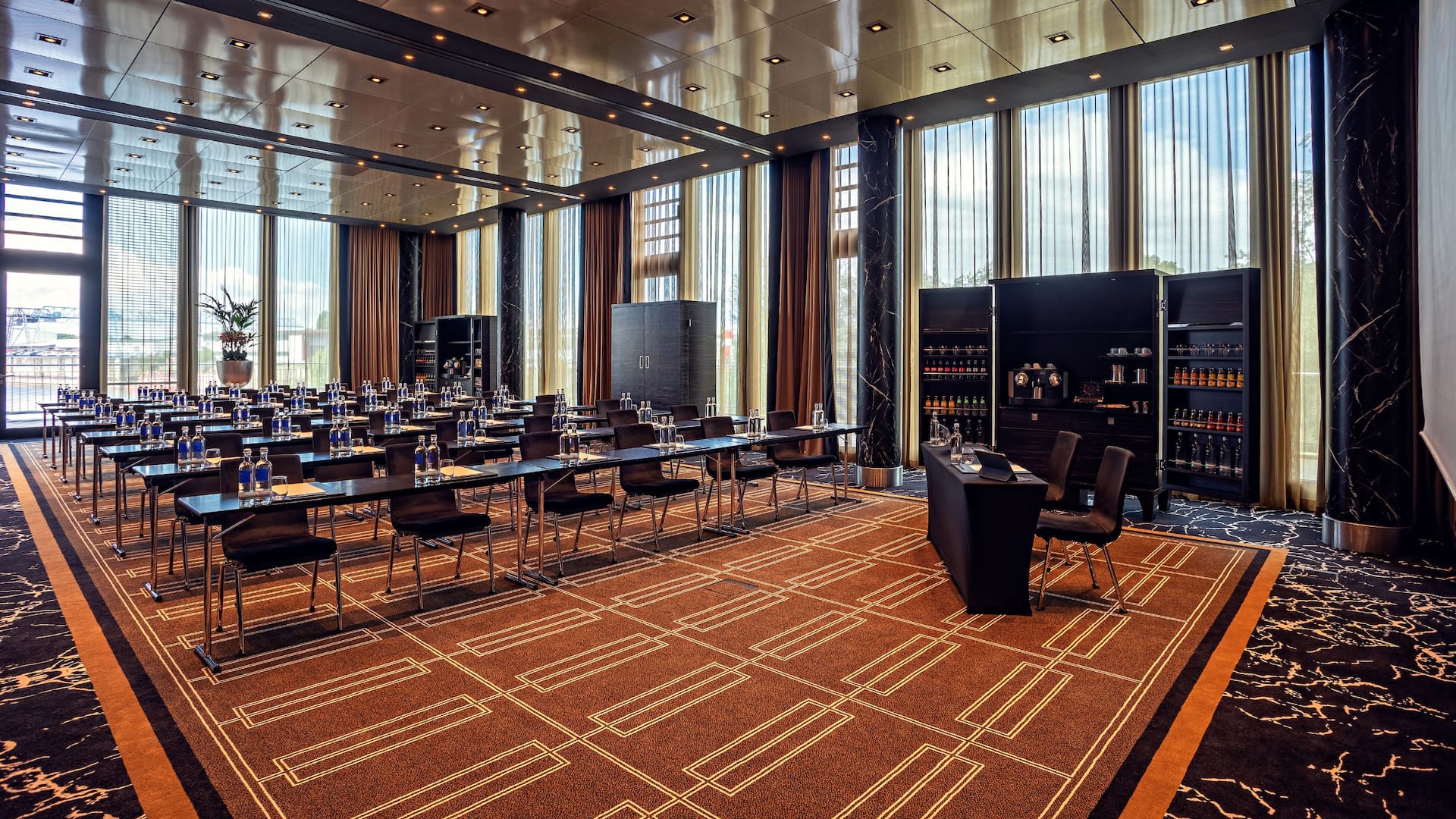 Conference room at the Hyatt Regency Dusseldorf, with rows of seats, tables, screen, floor to ceiling windows, coffee break