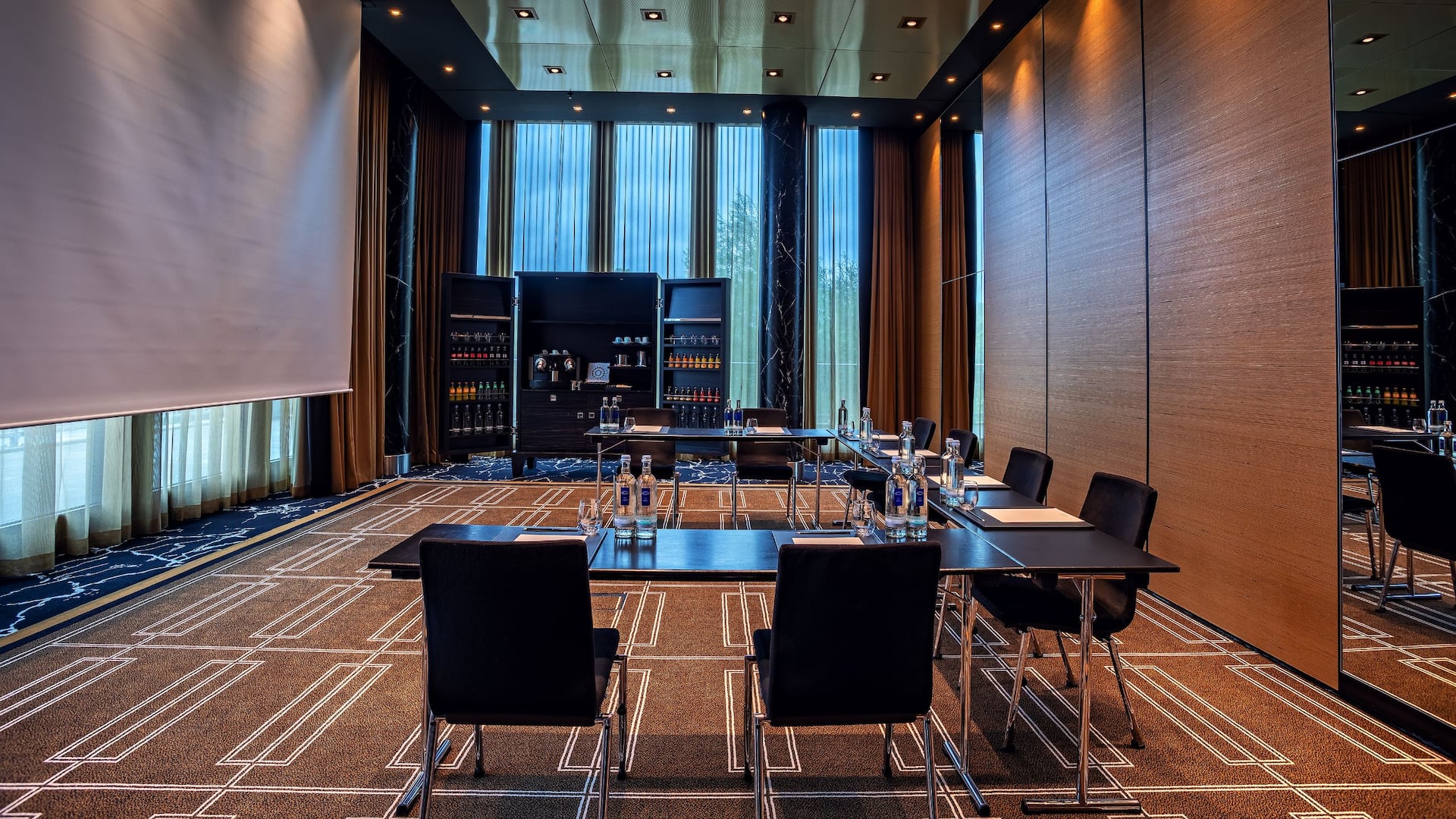 Meeting room in Hyatt Regency Dusseldorf seating, tables, screen, floor to ceiling windows, coffee break cabinet