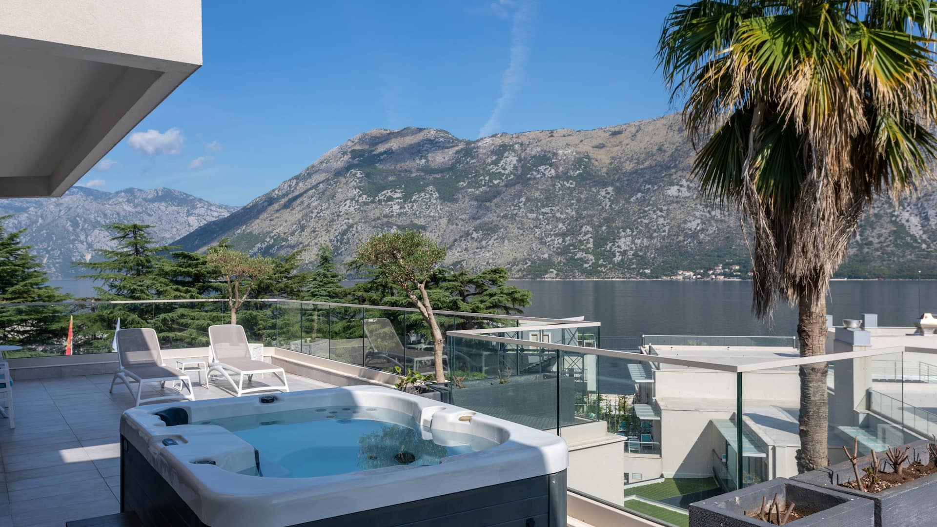 Luxury Sea View Suite at Hyatt Regency Kotor Bay Resort, Montenegro, featuring a private hot tub on the balcony with stunning sunset views over Kotor Bay.