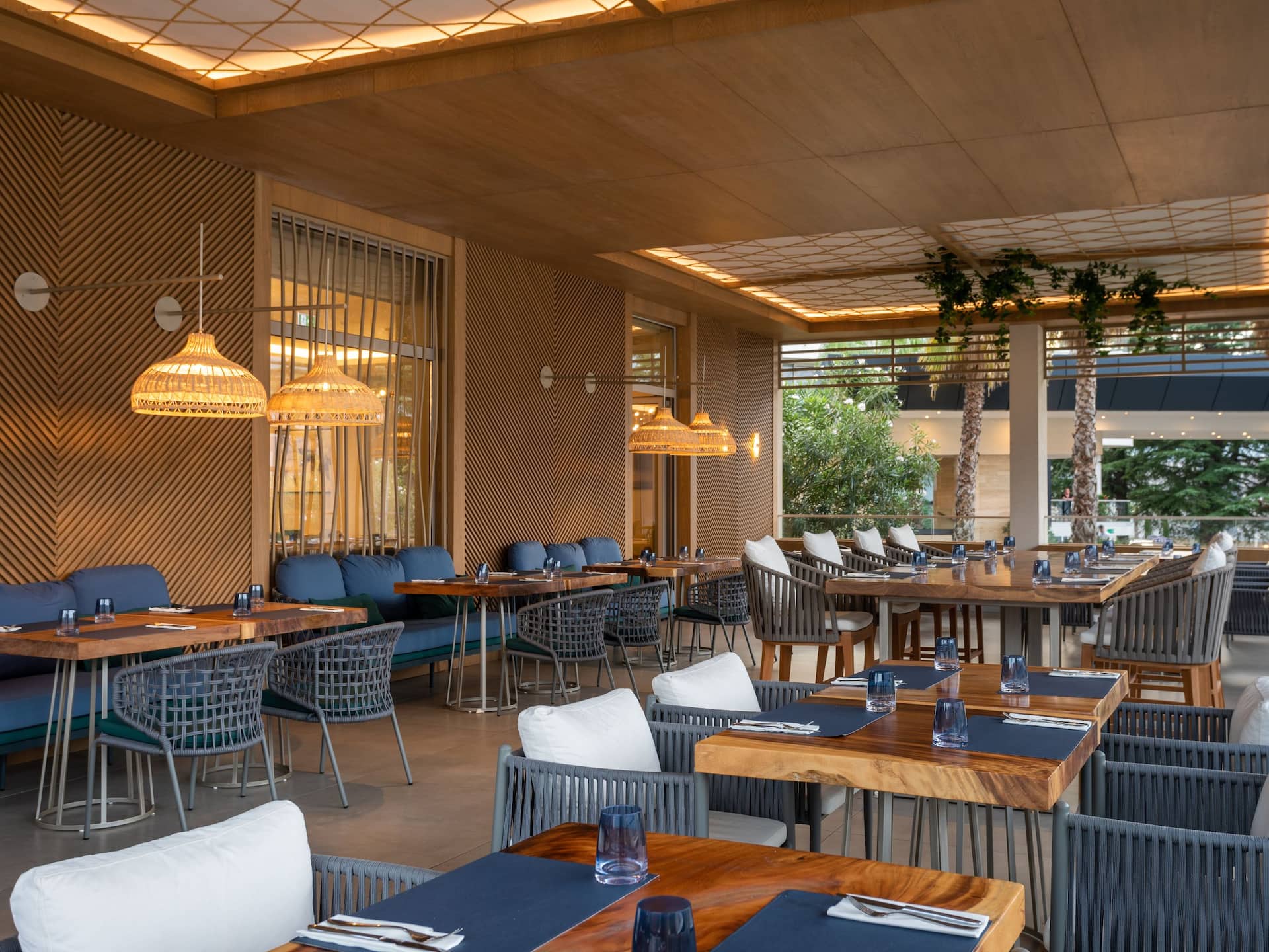 The interior of Blue Restaurant, featuring elegant wooden decor, comfortable seating, and neatly set tables with soft lighting, creating a warm and inviting dining atmosphere.
