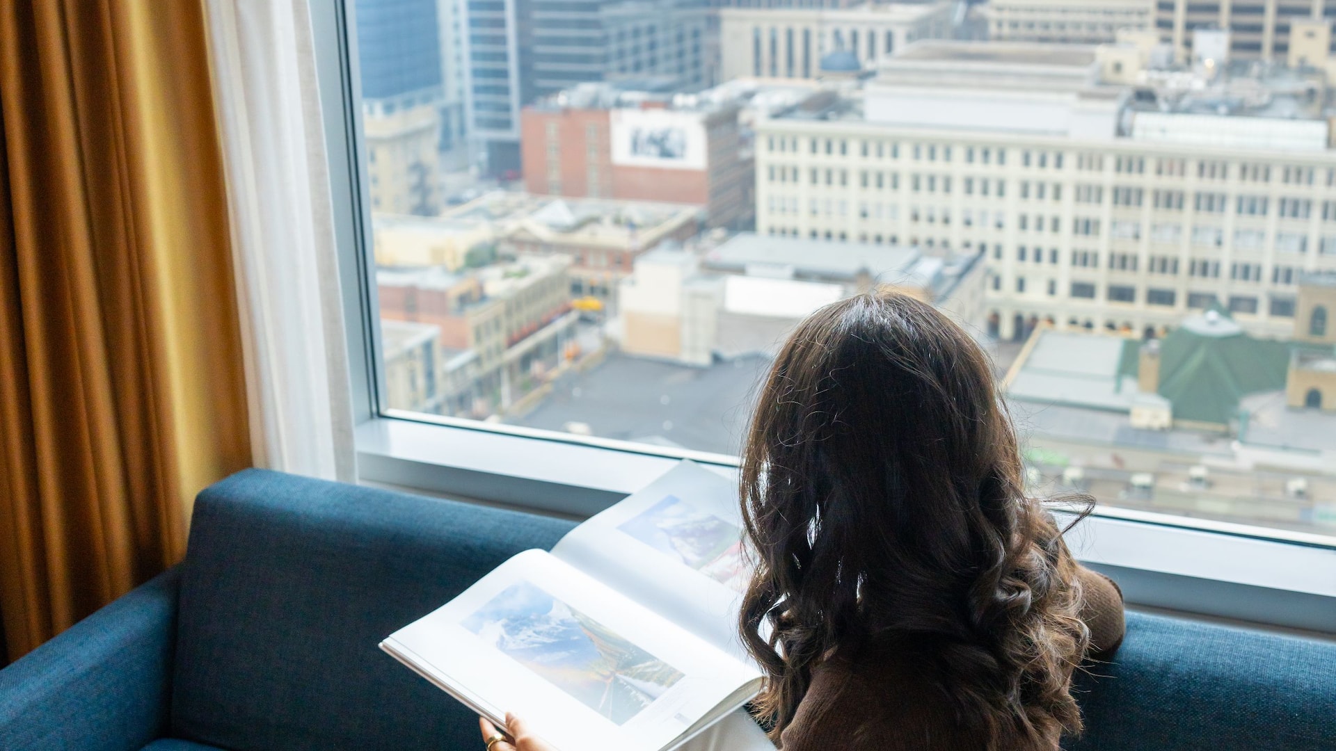 1 of 3 Hyatt Regency Calgary Guestroom City View Woman Sitting Window