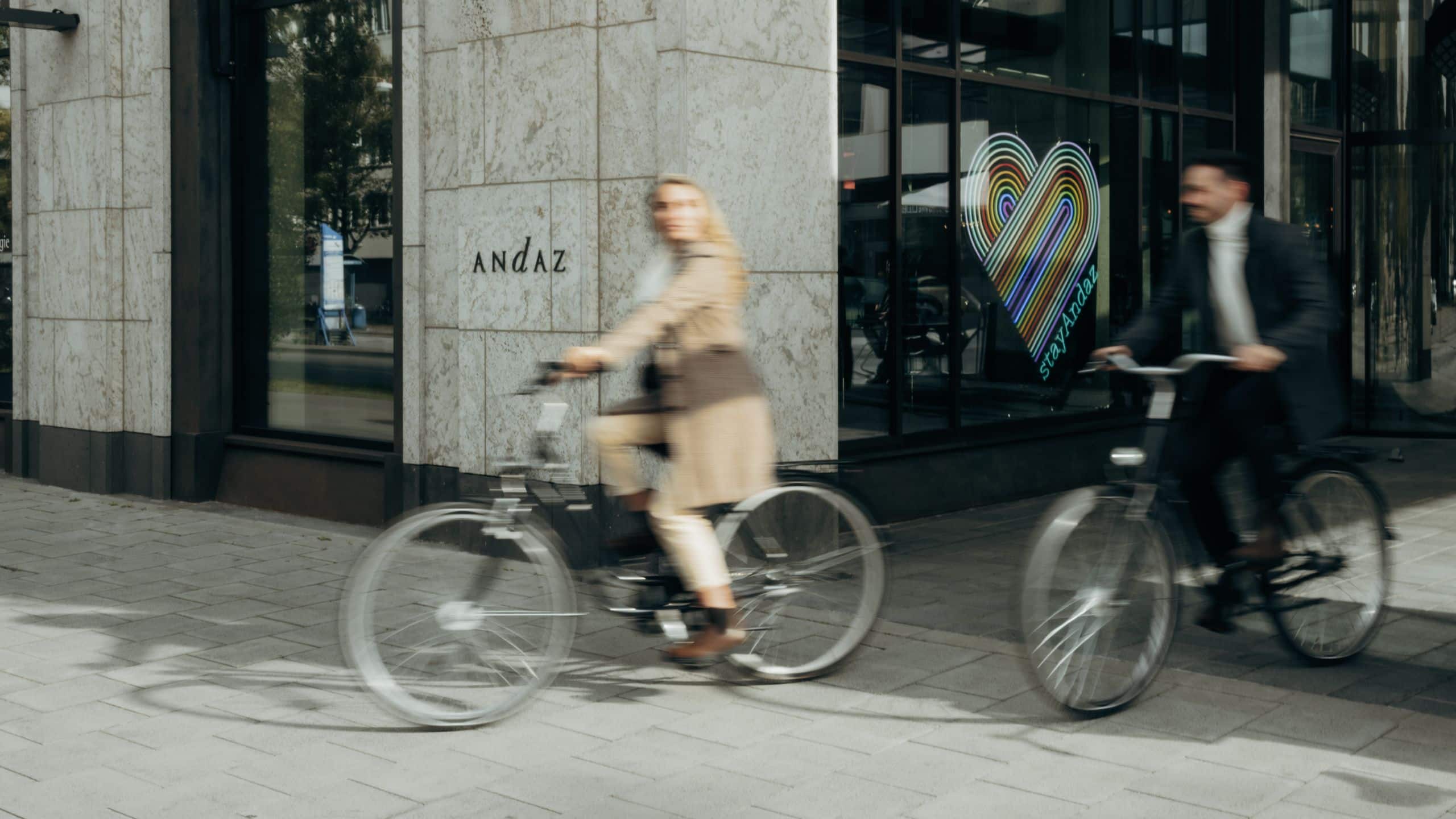 Zwei Radfahrer im Herbst vor dem Haupteingang des Andaz München Schwabinger Tor