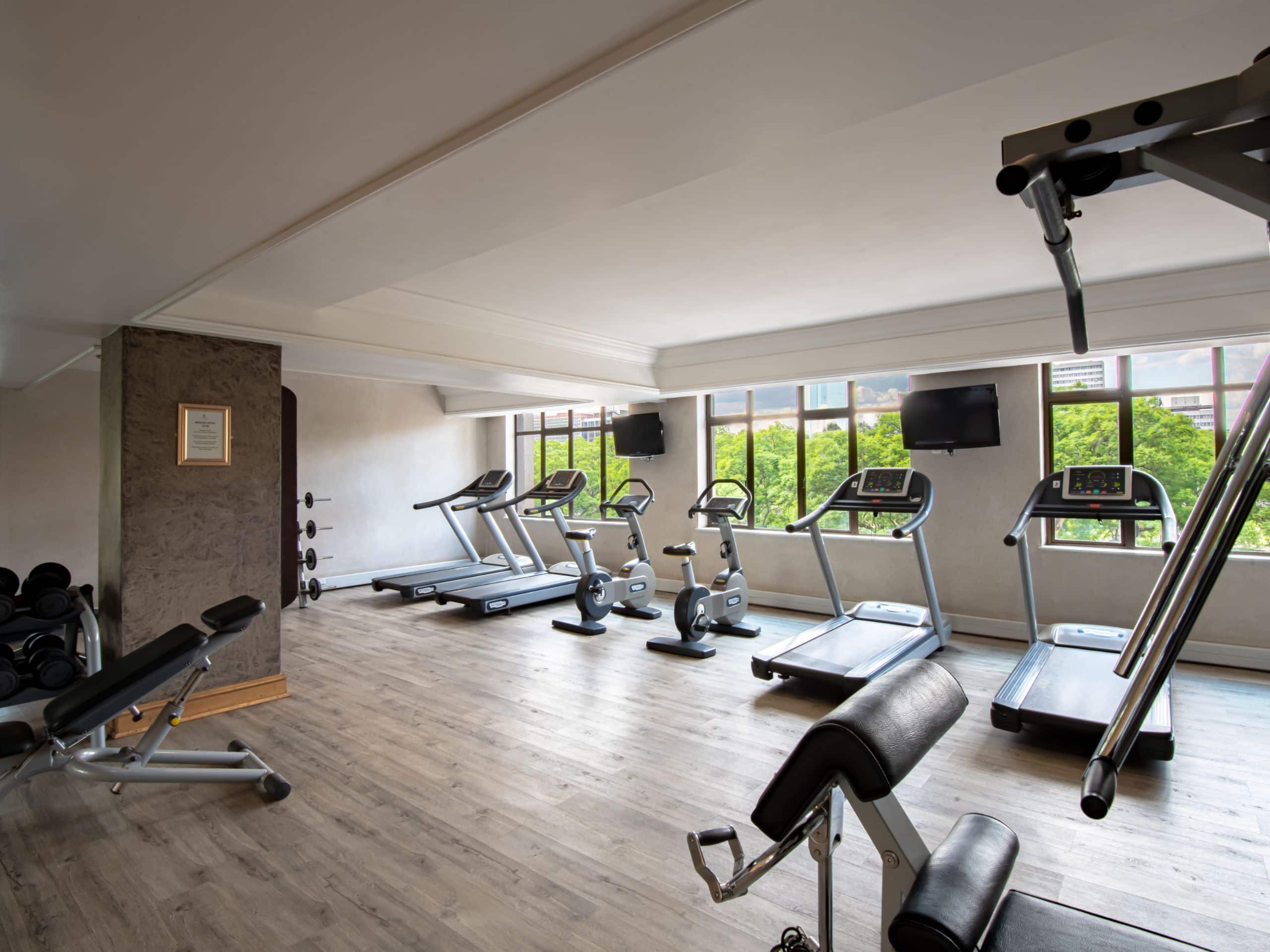 A luxury hotel gym at Hyatt Regency Harare The Meikles, featuring treadmills and a large window offering stunning views.
