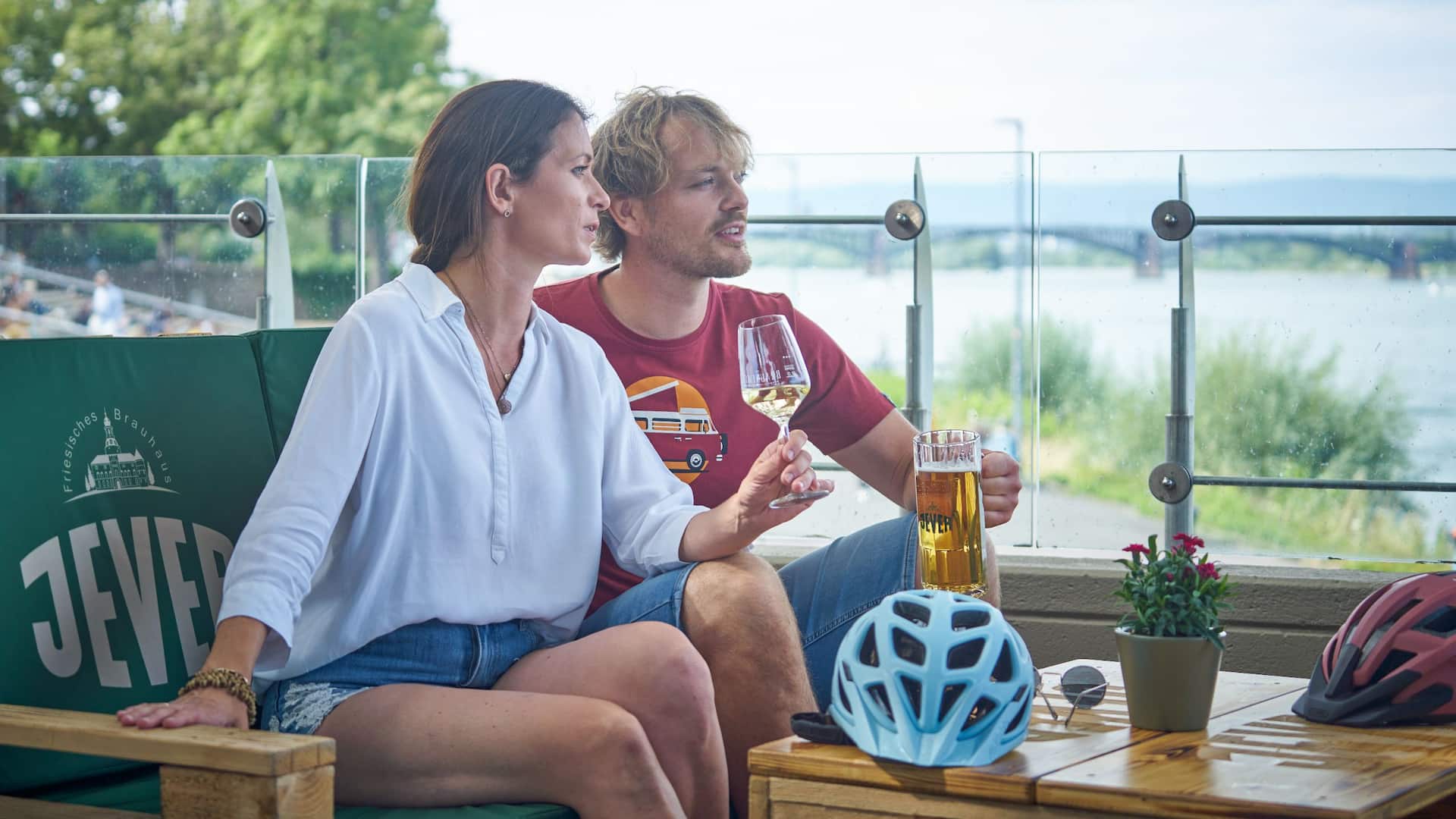 Ein Pärchen sitzt mit Wein und Bier in der Hand im Biergarten des Hyatt Regency Mainz und betrachtet dabei den Rhein.