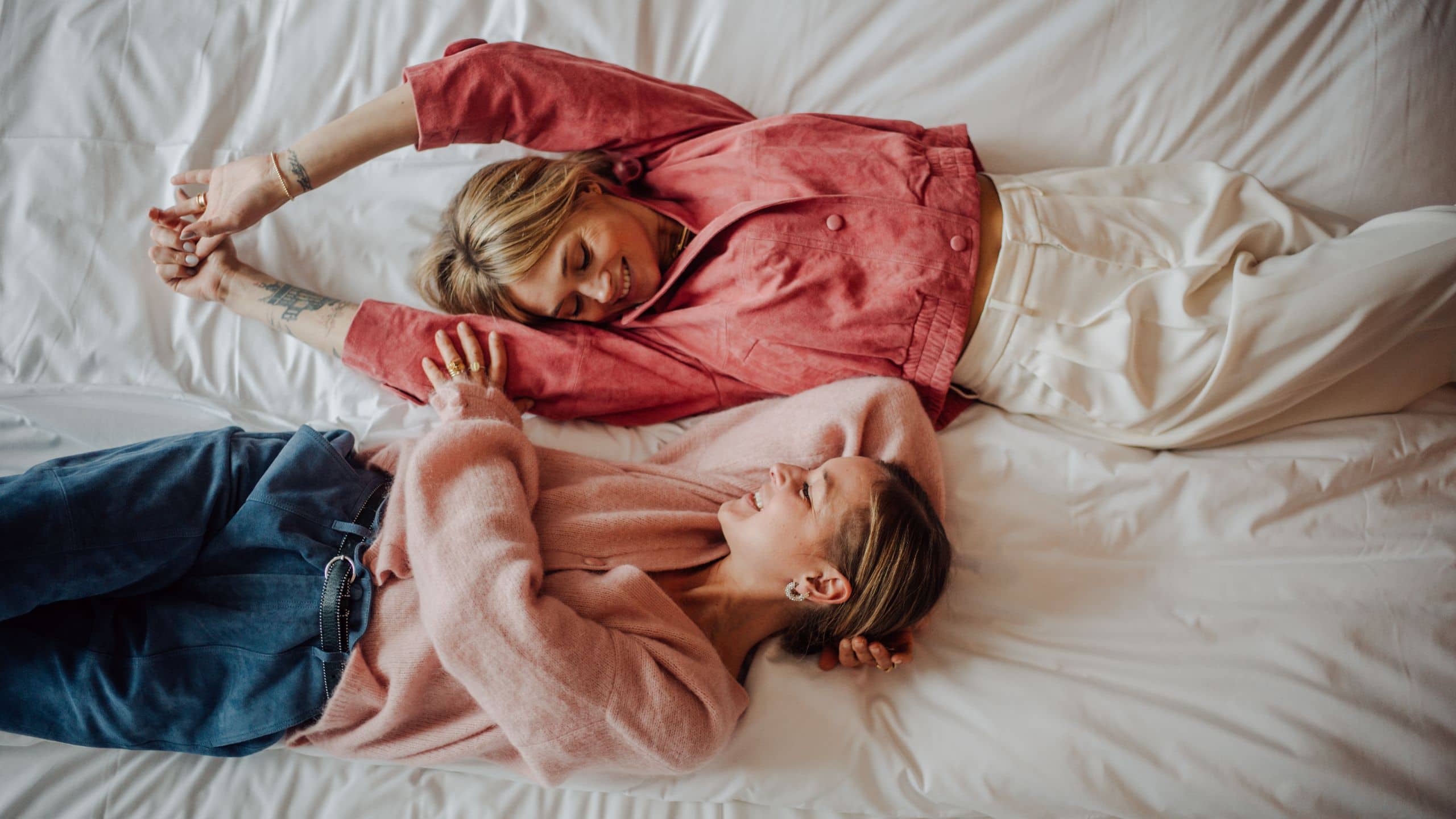 Two friends relaxing on bed in guest room of Andaz Munich hotel
