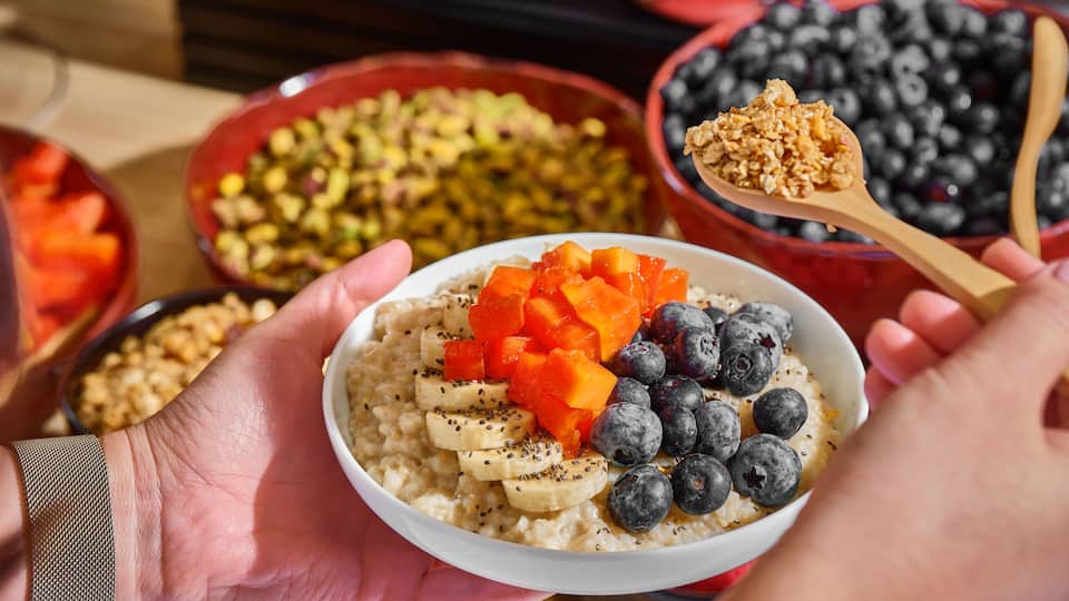 Hands holding a colorful fruit granola bowl