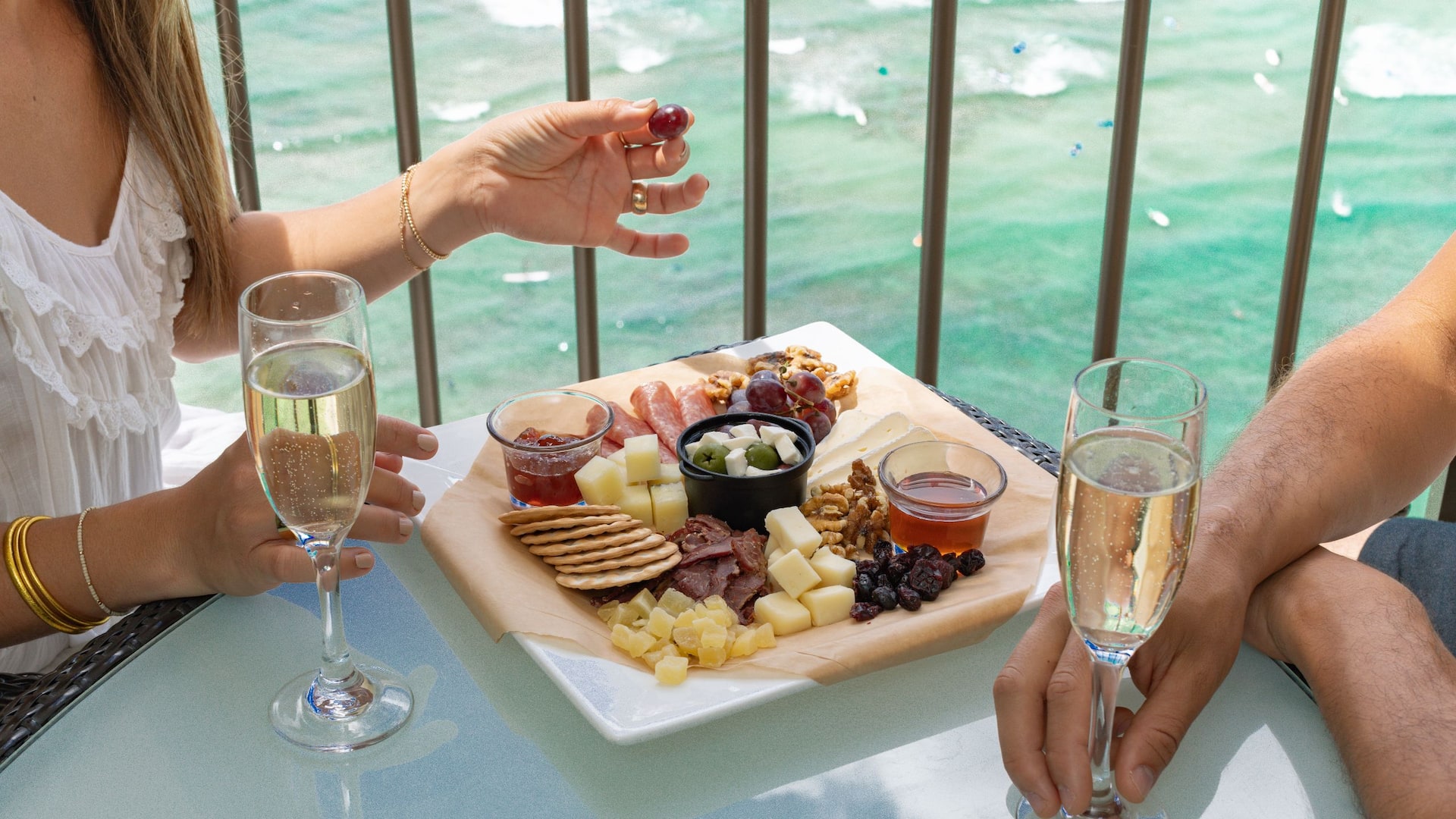 Hyatt Regency Waikiki Beach Resort and Spa Couple Enjoying In Room Charcuterie And Holding Champagne