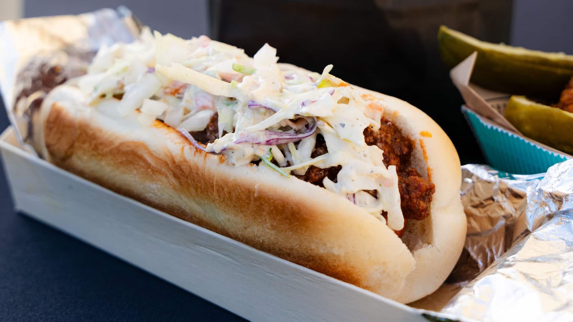 Ein Hotdog gefüllt mit Fleisch und  asiatischem Salat im Biergarten des Hyatt Regency Mainz.